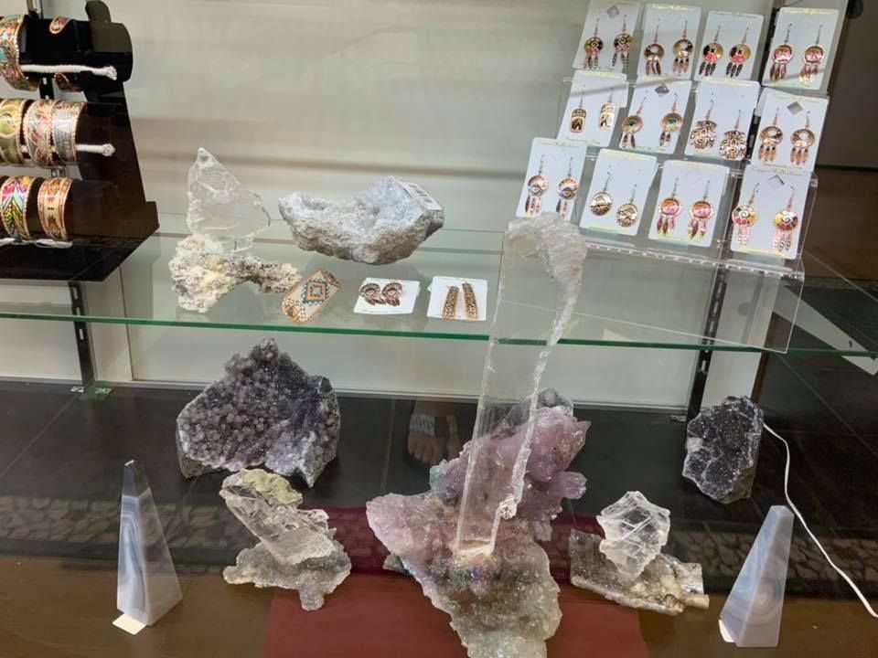 Jewelry display case with crystals and earrings. Pink, gray, and white stones and cards of dangling earrings.