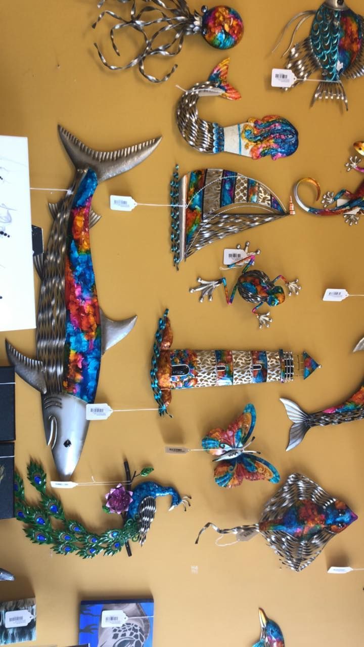 Metal art of colorful fish and marine life against a yellow background.