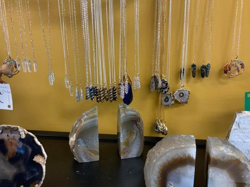 Jewelry display with necklaces hanging on a yellow wall, agate bookends on a black shelf.