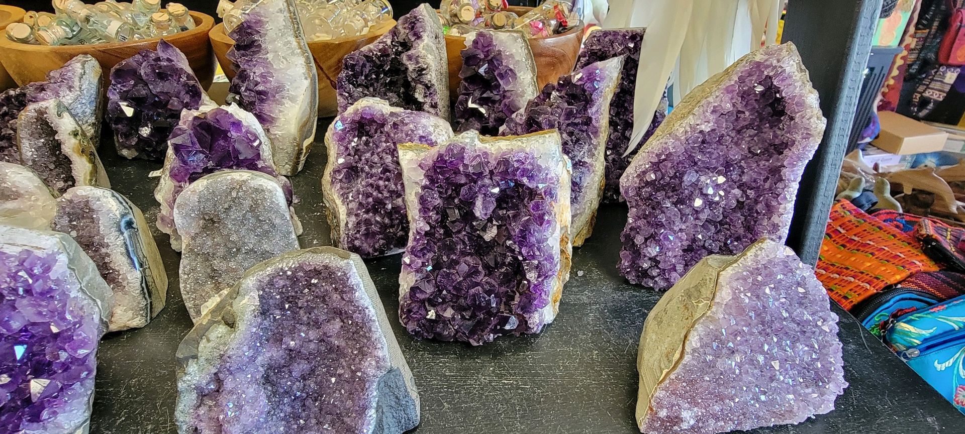 Amethyst crystals on display, varying in size and shape, purple color.