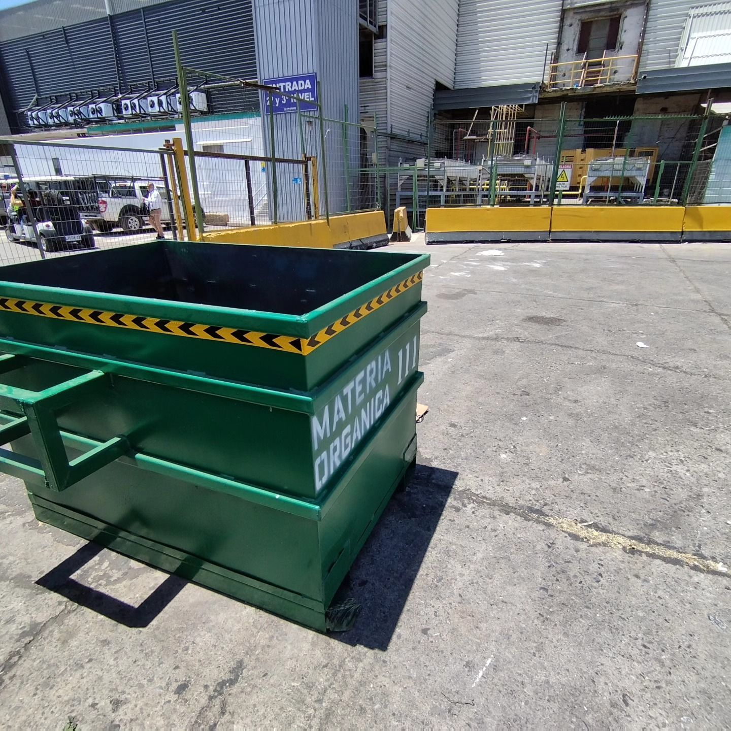Un contenedor de basura verde está tirado al costado de la carretera frente a un edificio.