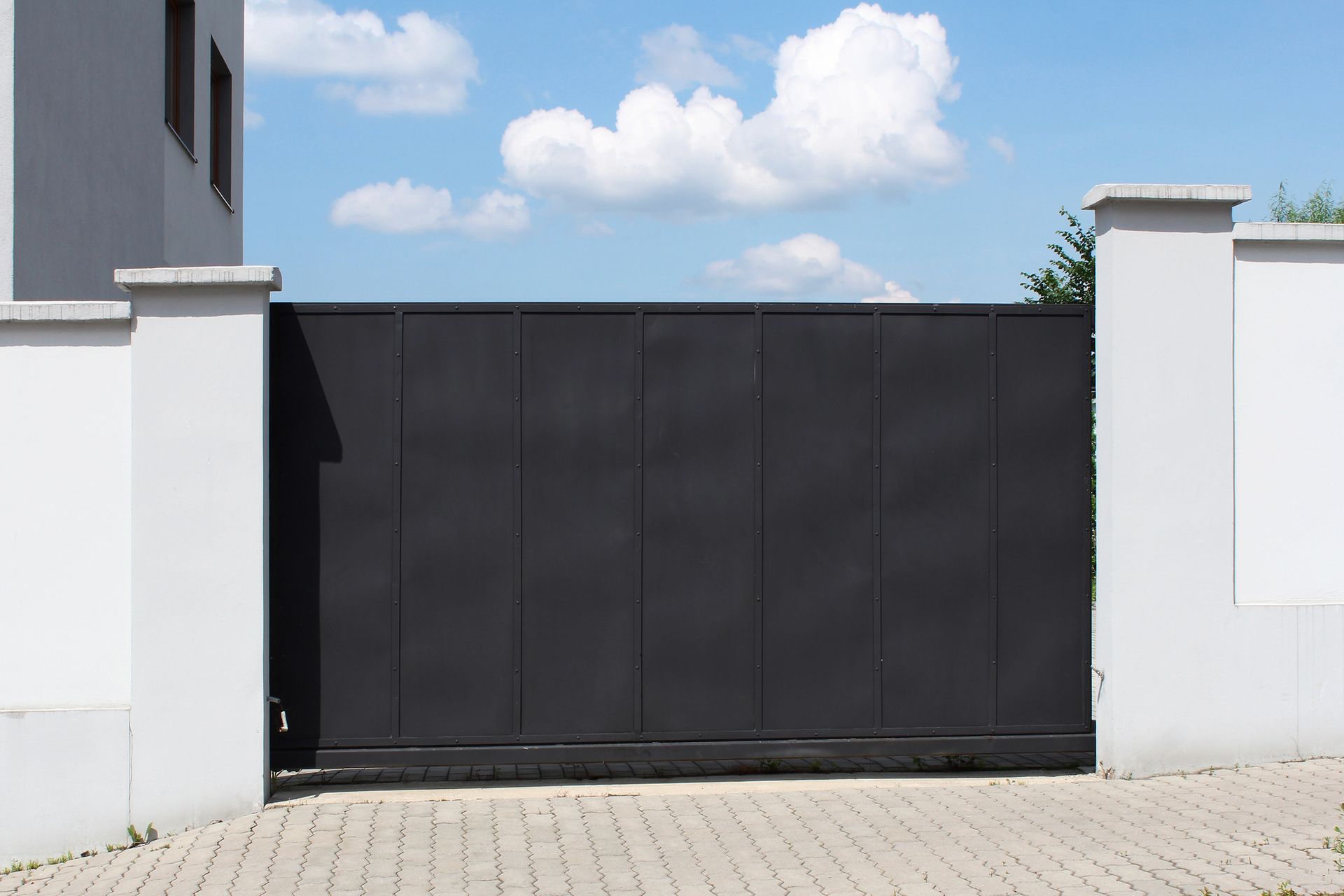 Una puerta corrediza negra se encuentra frente a un edificio blanco.