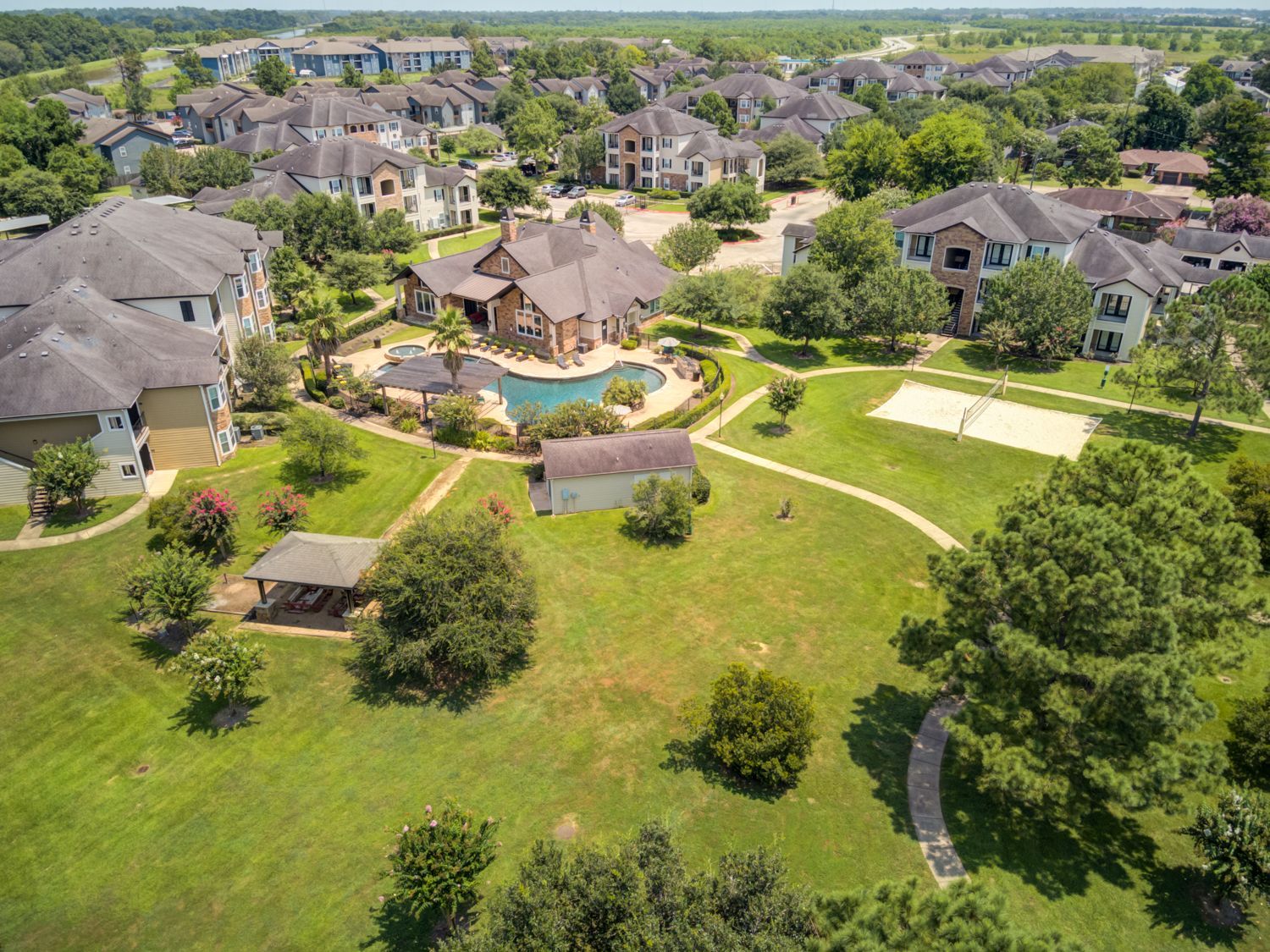 A large lush green field with a fence and trees in the background.