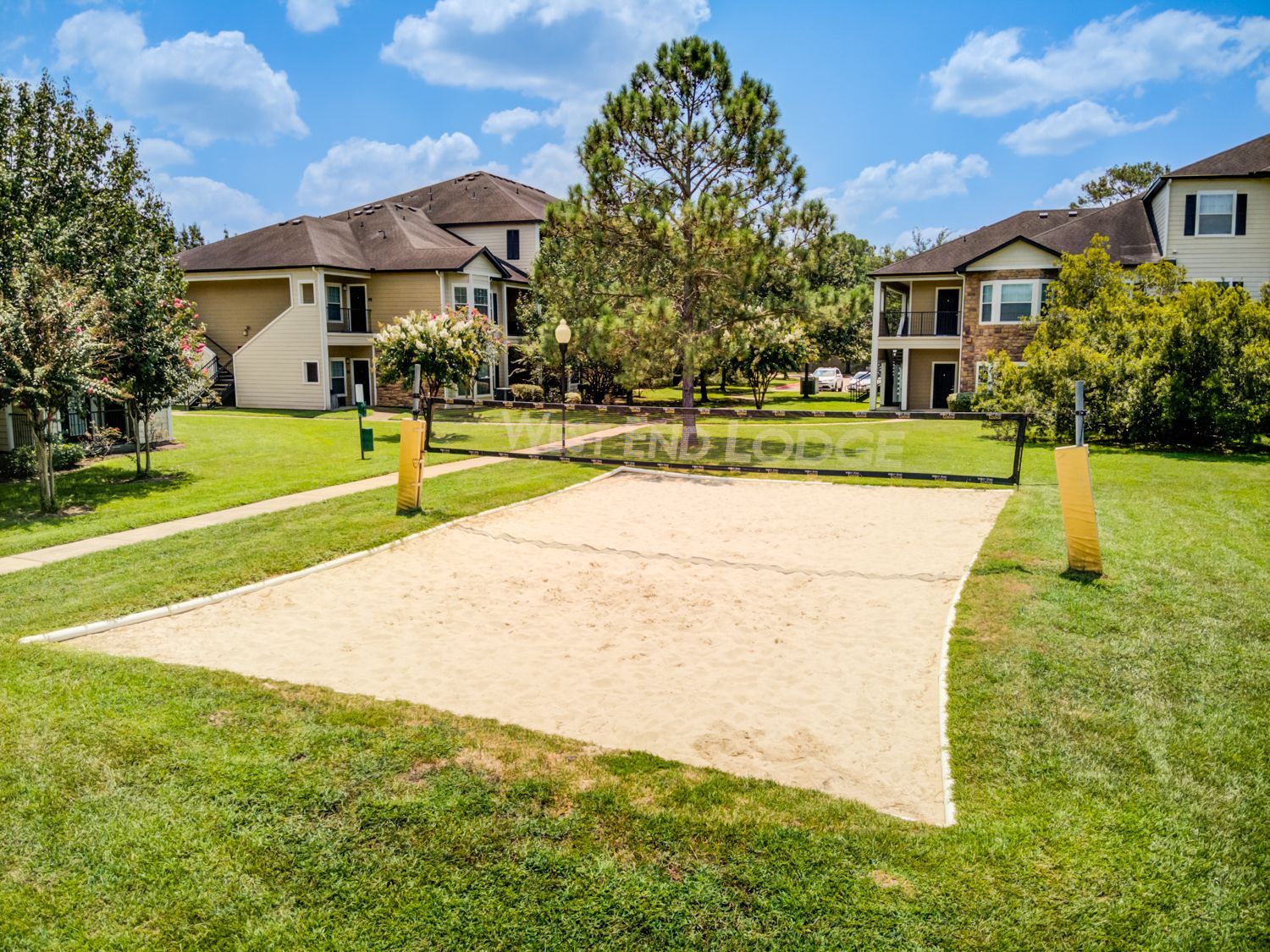 A volleyball court in a park with a building in the background.