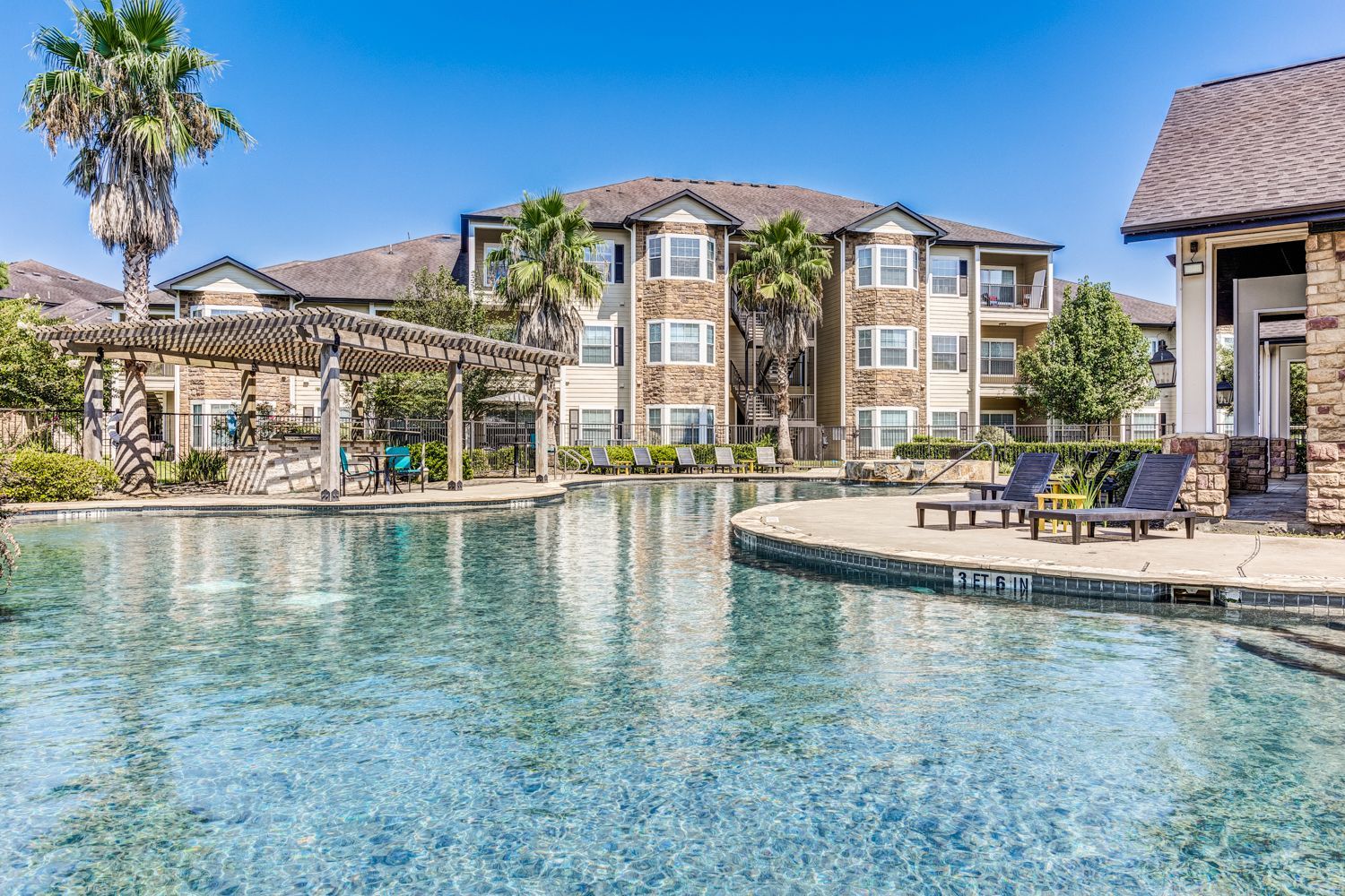 A large swimming pool in front of a large apartment building.