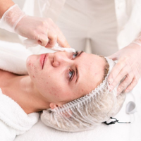 Facial treatment on a woman lying on a spa bed, with a beautician applying cream near her eye.