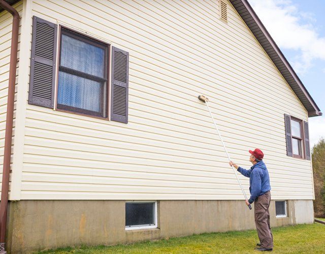 Vinyl Siding — Man Cleaning Mold From Vinyl Siding in Fayetteville, NC