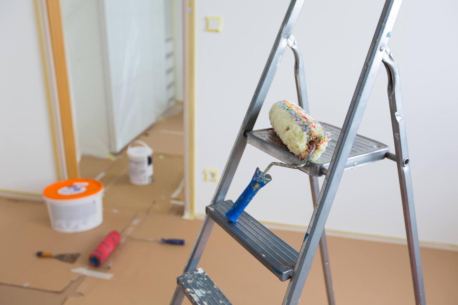 A paint roller is sitting on top of a ladder.