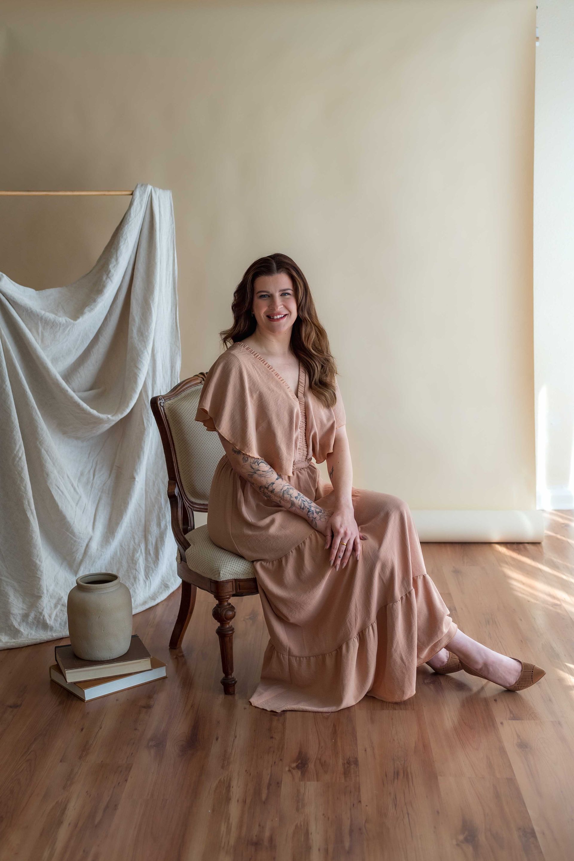 A woman in a long dress is sitting in a chair.