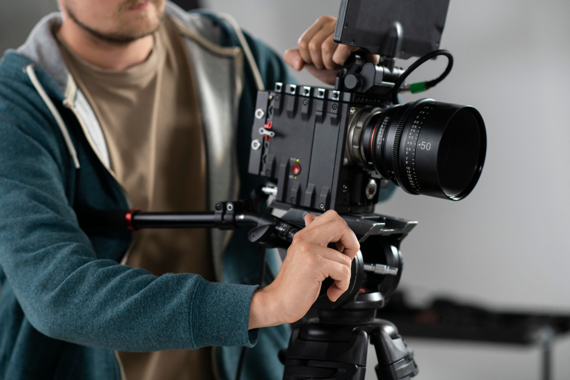 A man is adjusting a video camera on a tripod.