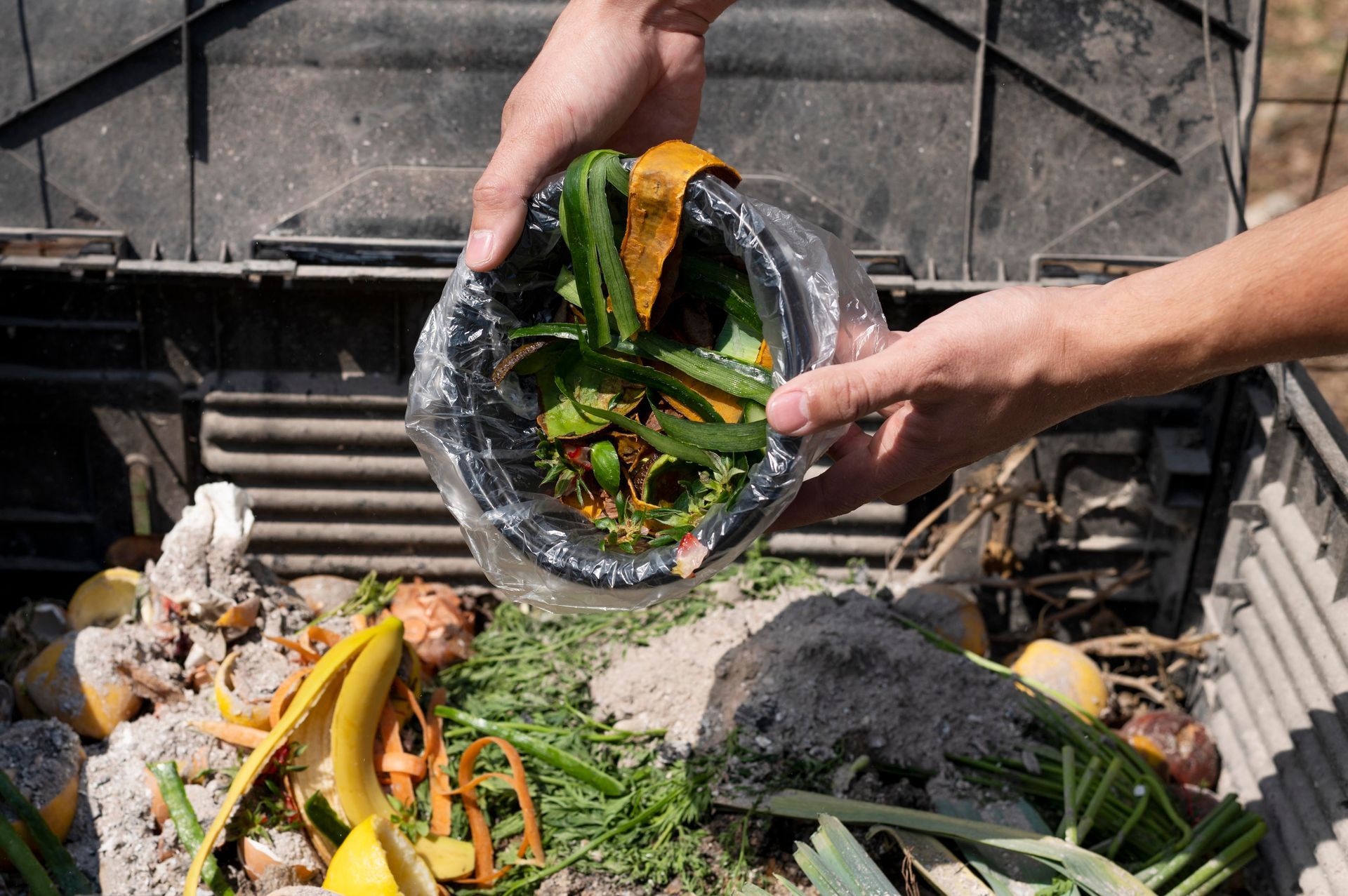 A person is putting food waste into a trash can.