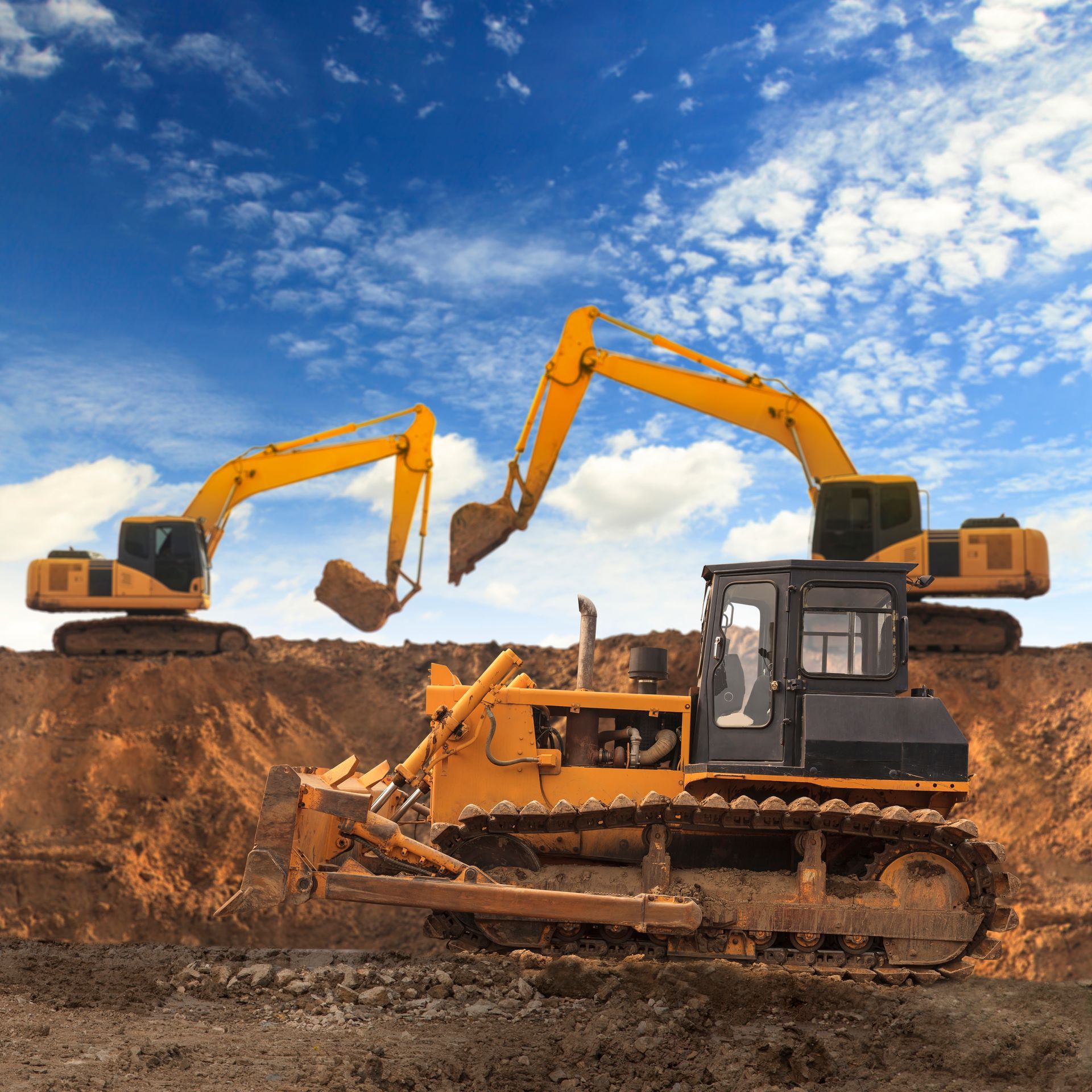 Two bulldozers are working on a construction site.