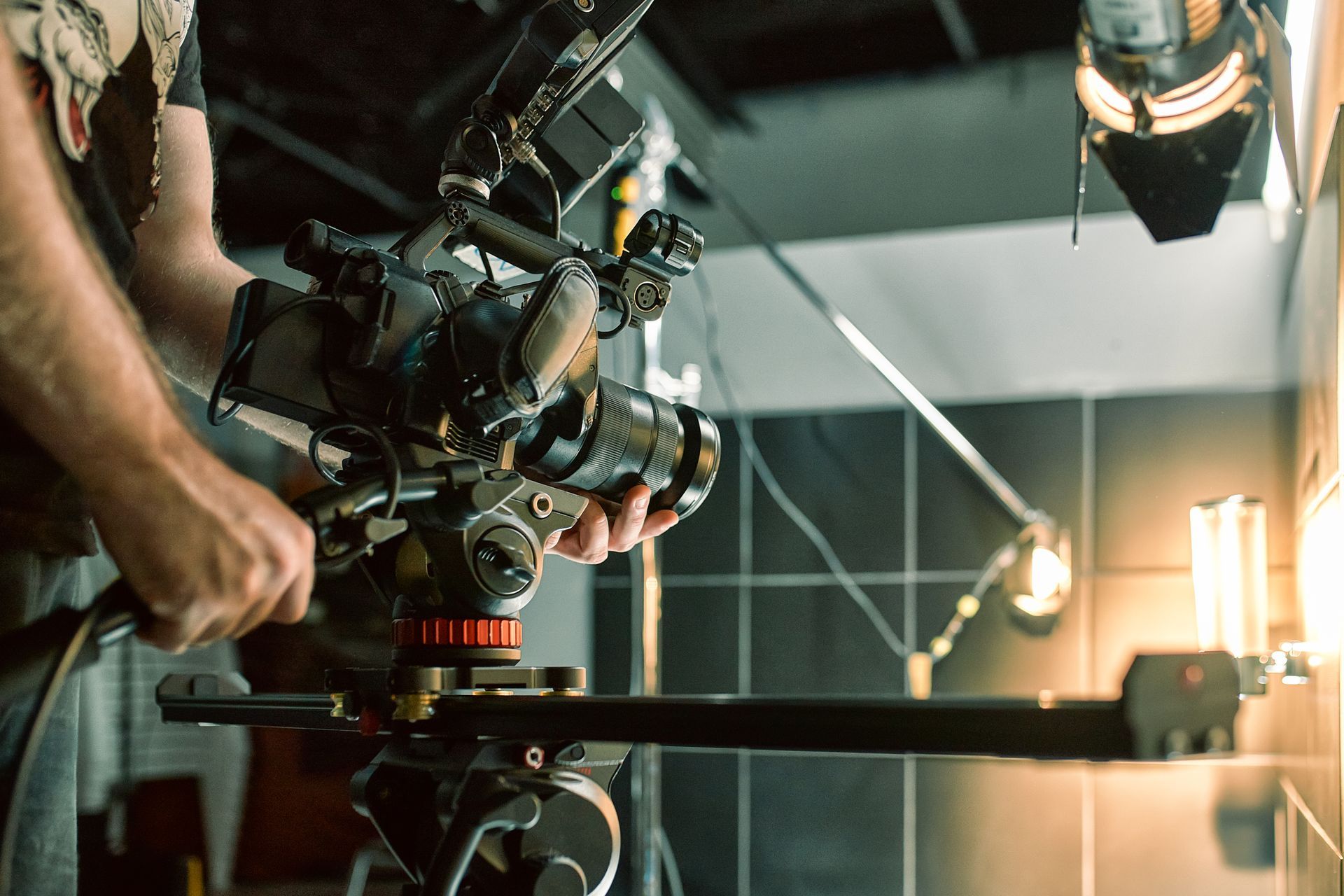 A man is holding a camera on a tripod in a dark room.