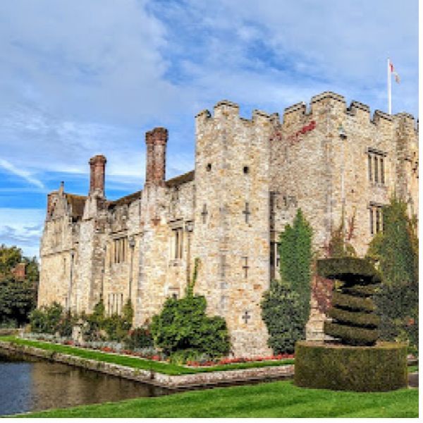 A large stone castle with a pond in front of it