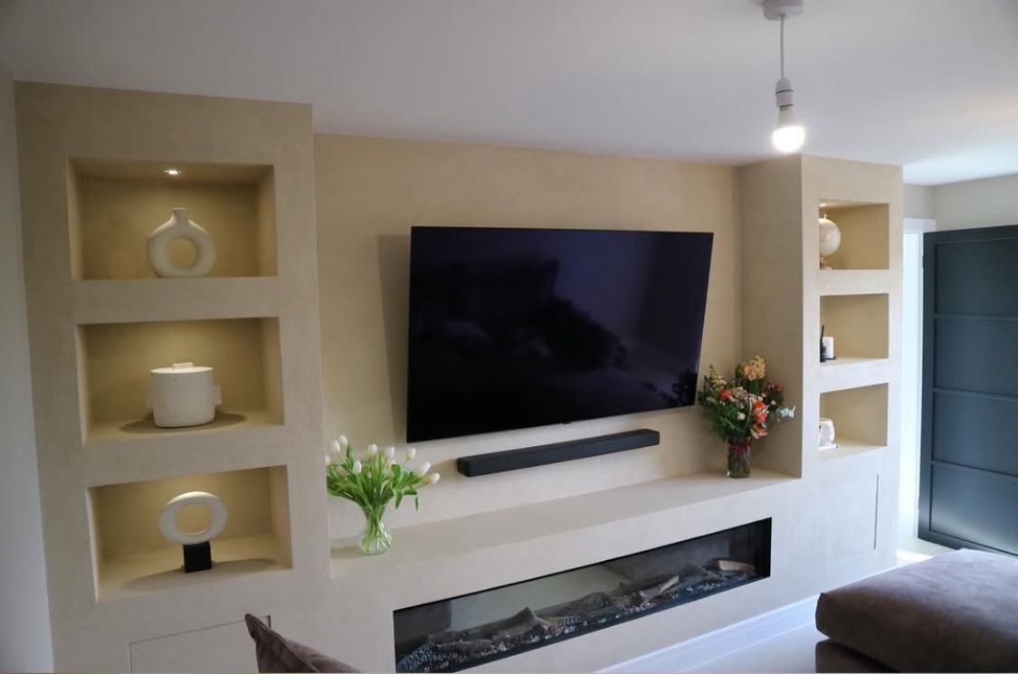 A living room with a fireplace and a flat screen tv on the wall.
