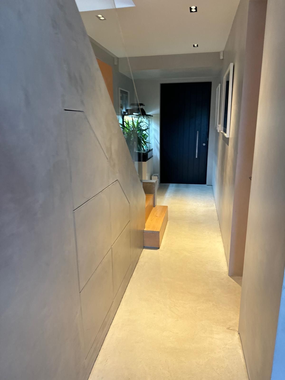 A long hallway with stairs leading up to a door.