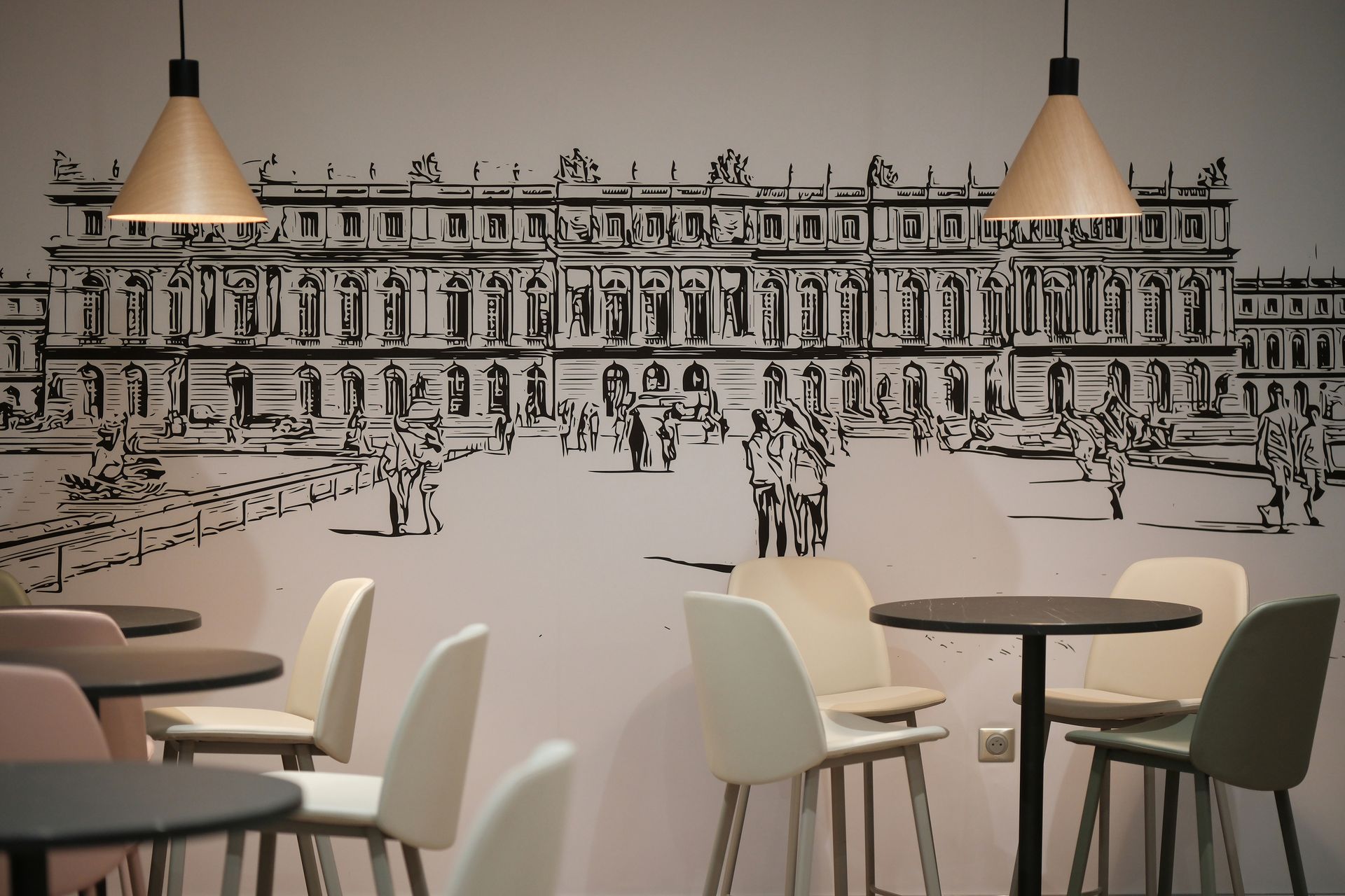 Une pièce avec des tables et des chaises et un dessin d'un bâtiment sur le mur