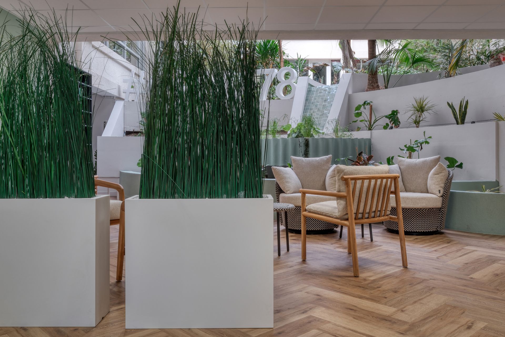 Un salon avec un parquet, des chaises, des tables et des jardinières.