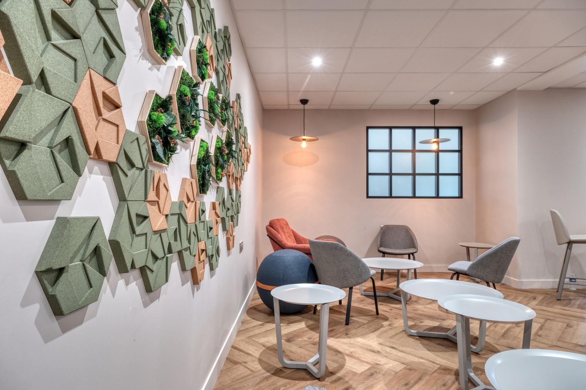 Une pièce avec des tables et des chaises et un mur avec une sculpture dessus.