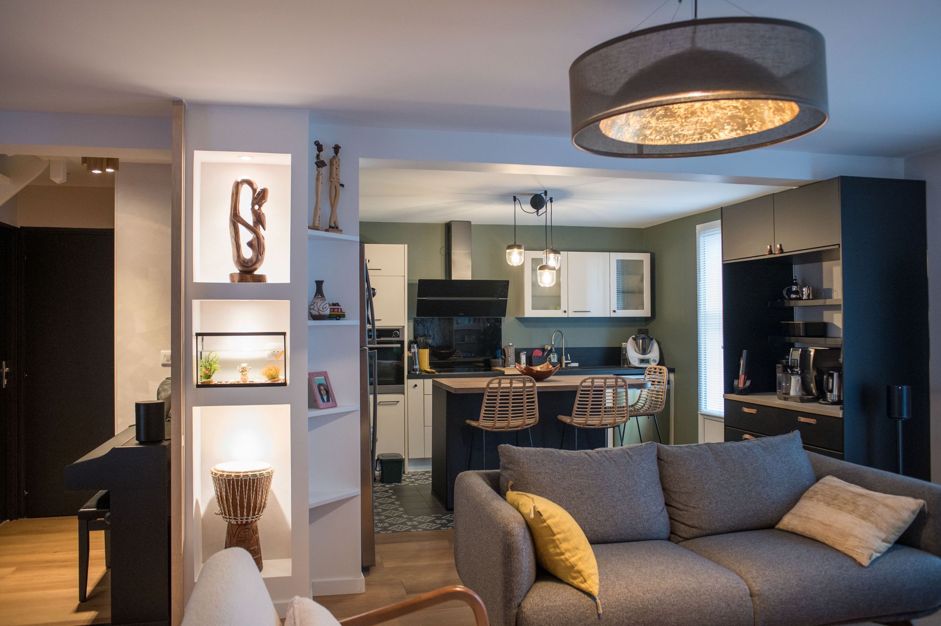 Un salon avec un canapé et une cuisine en arrière-plan.