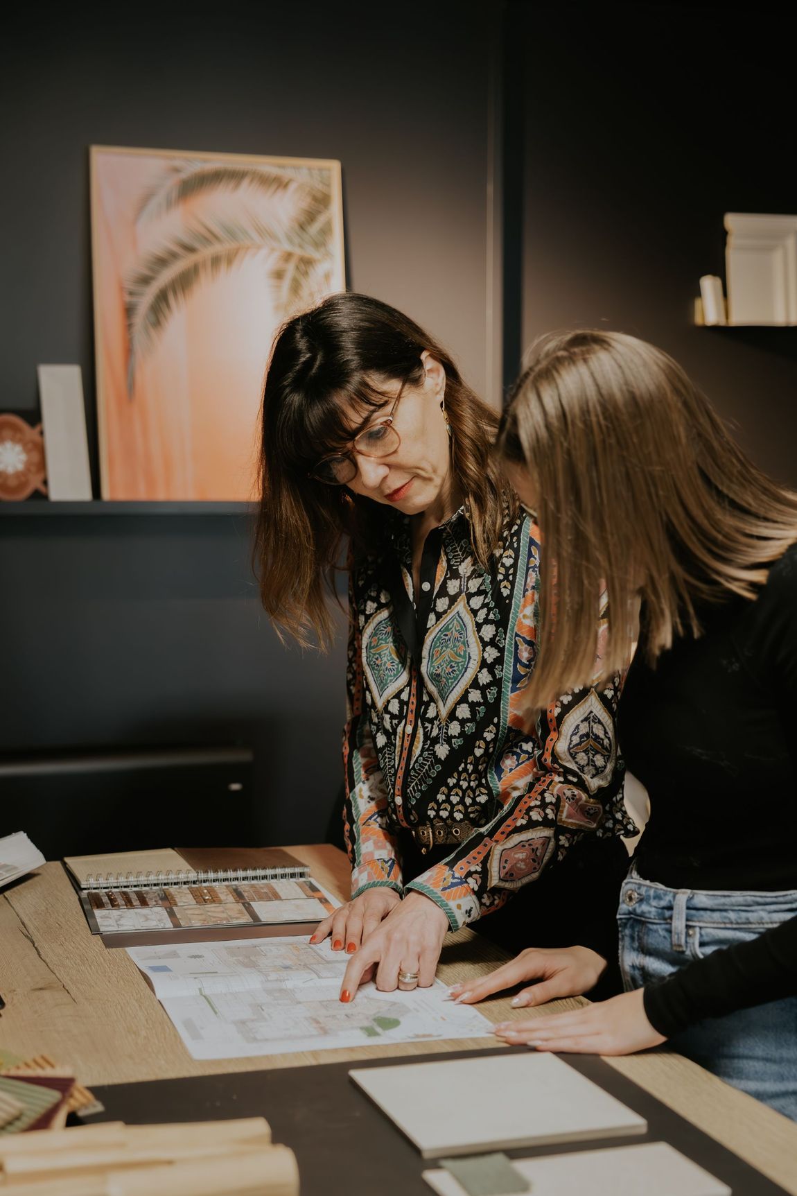 Deux femmes sont assises à une table et regardent un morceau de papier.