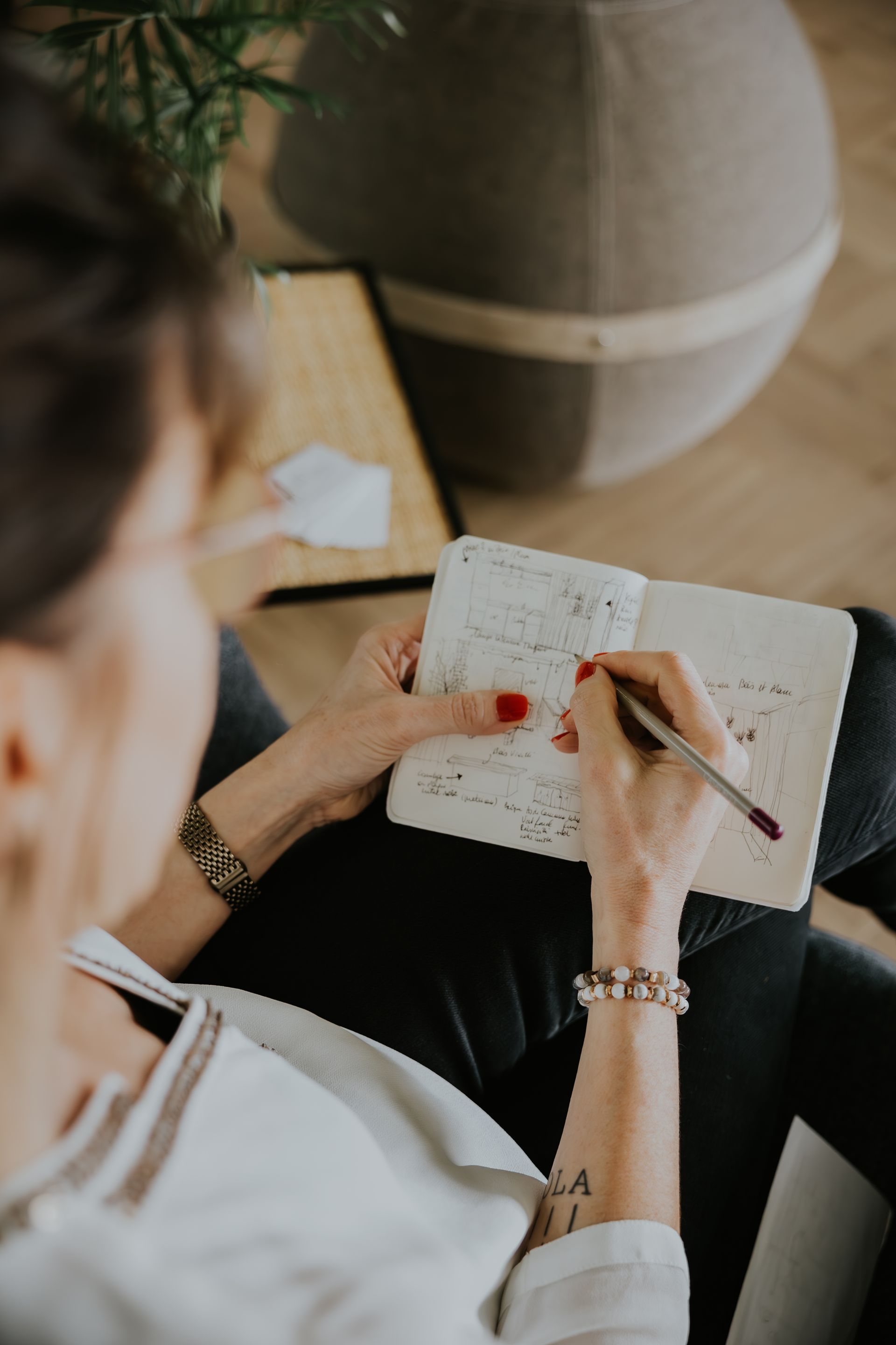Une femme est assise sur un canapé et écrit dans un cahier.