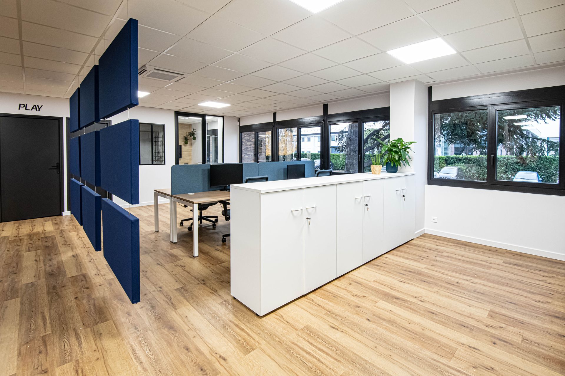 Un grand bureau avec parquet et mur bleu.