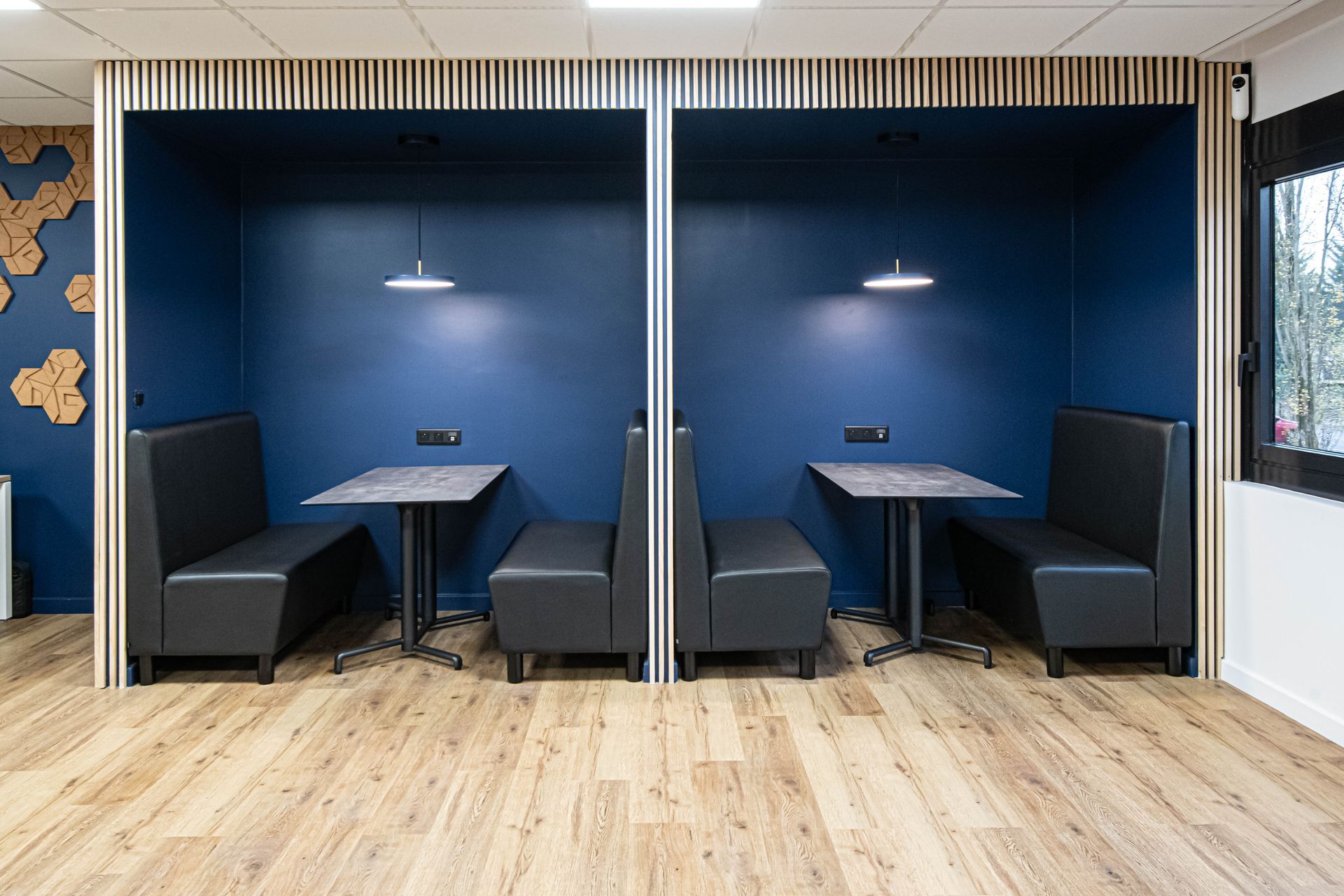 Une rangée de cabines avec des tables et des bancs dans une pièce aux murs bleus.