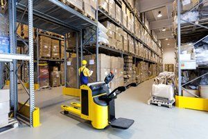 Huge metal stillage and yellow hand pallet truck in warehouse