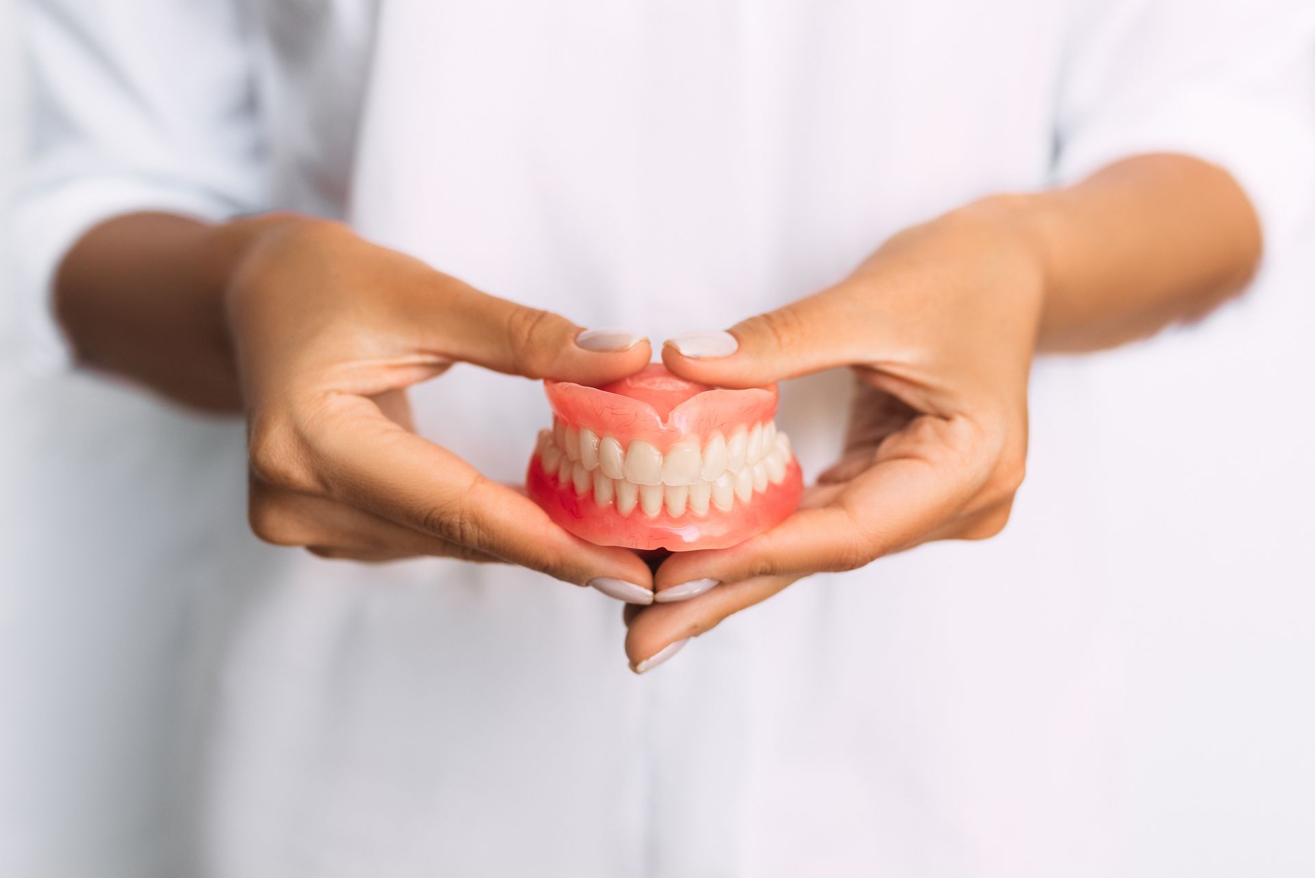 Hands holding a pink dental model against a white background