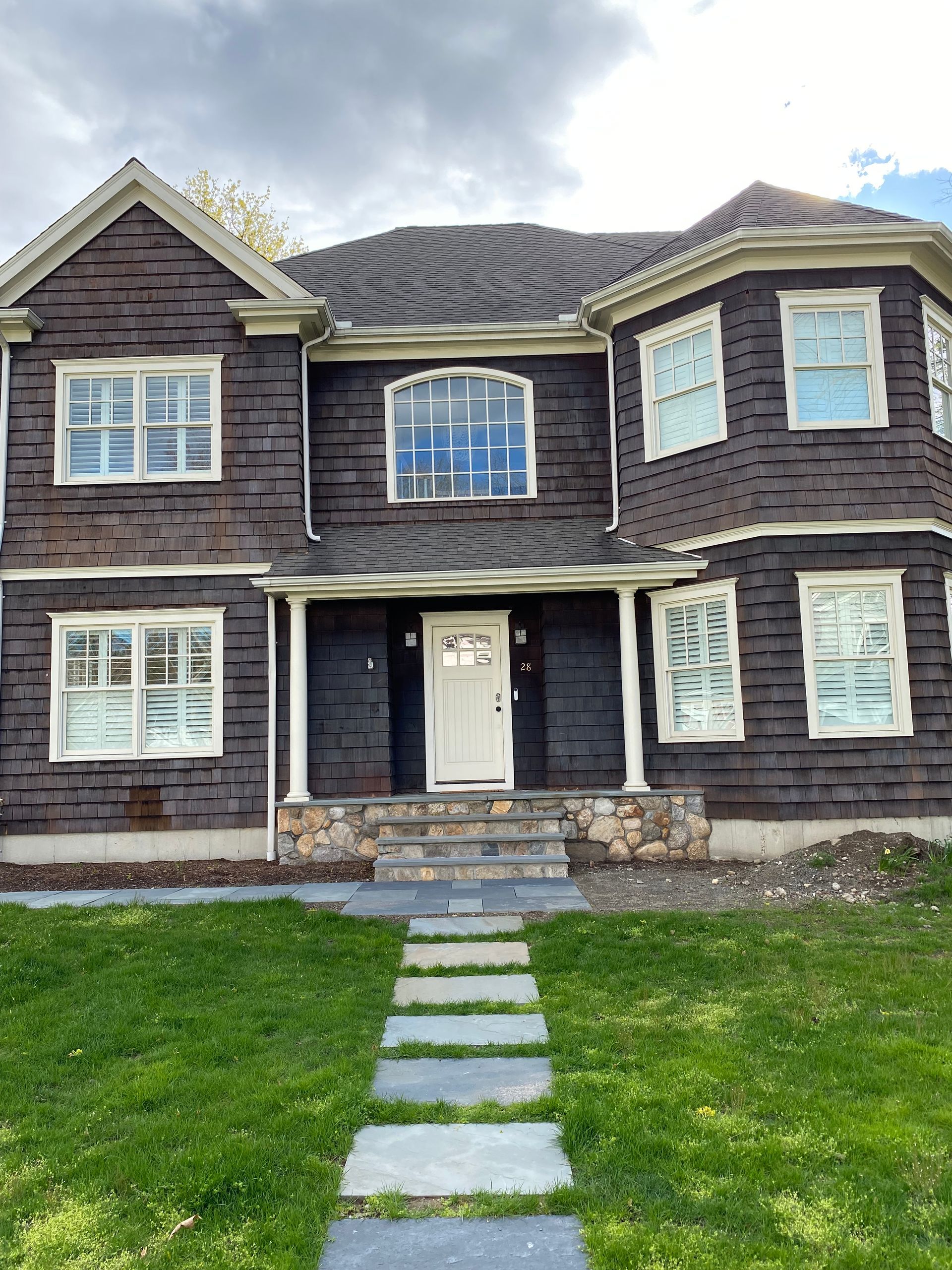 A large brown house with a stone walkway leading to the front door.