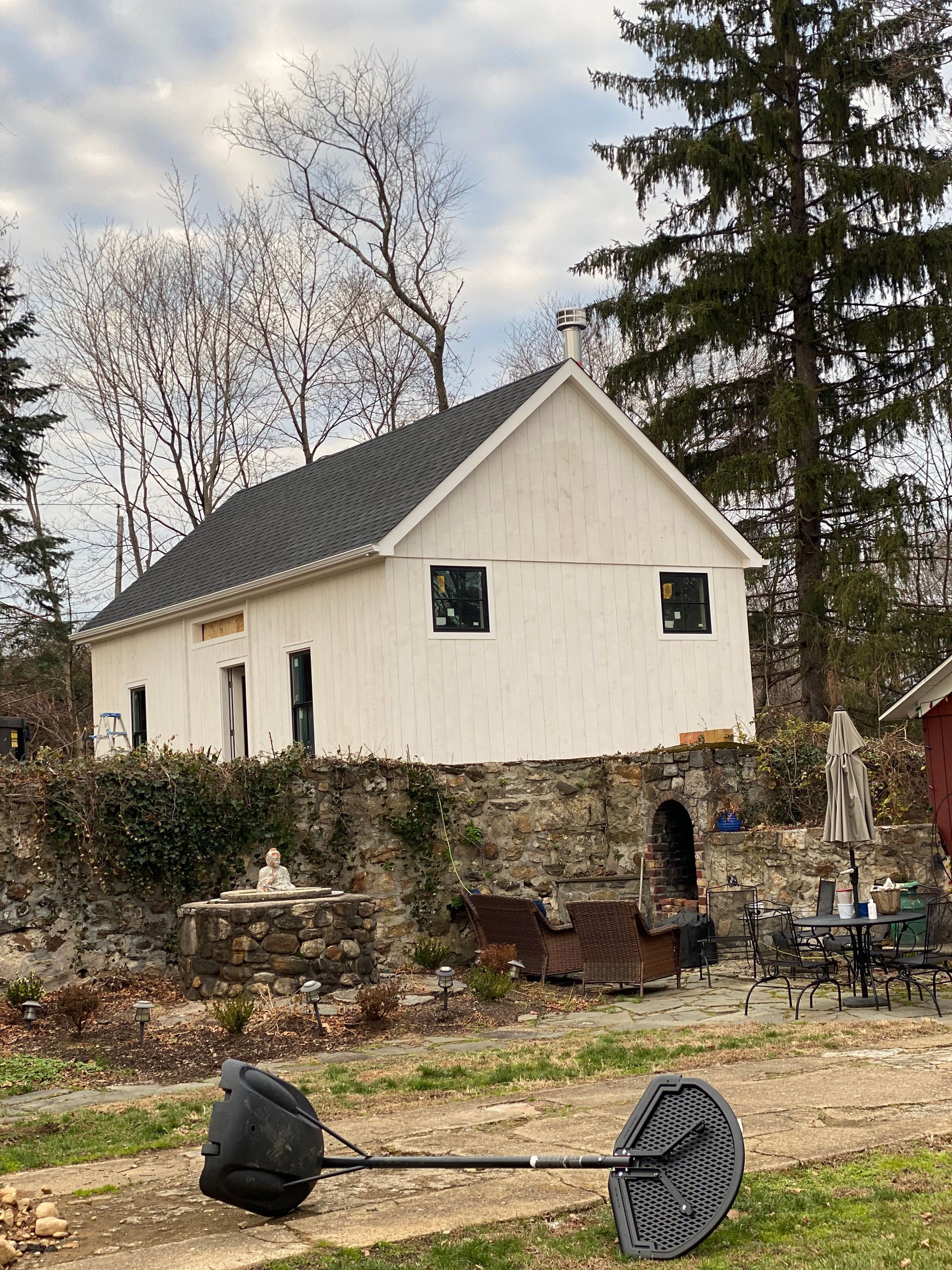 A white house with a black roof is surrounded by trees.