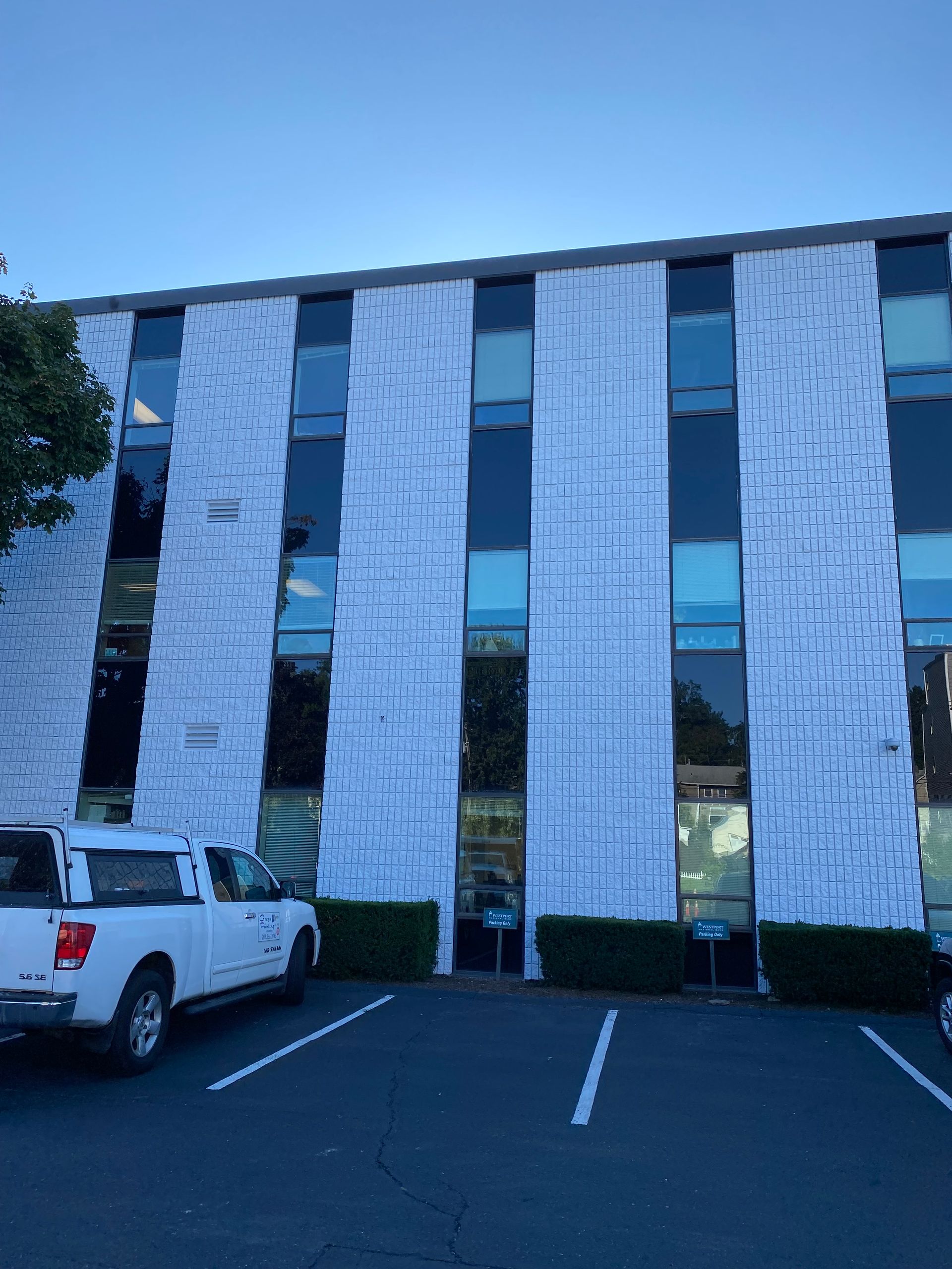 A white truck is parked in front of a building with a lot of windows.
