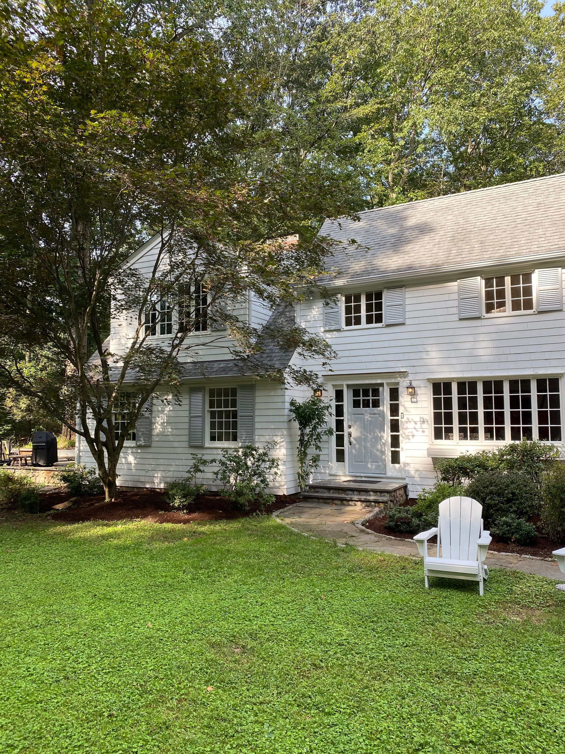 A white house with a large lawn in front of it.