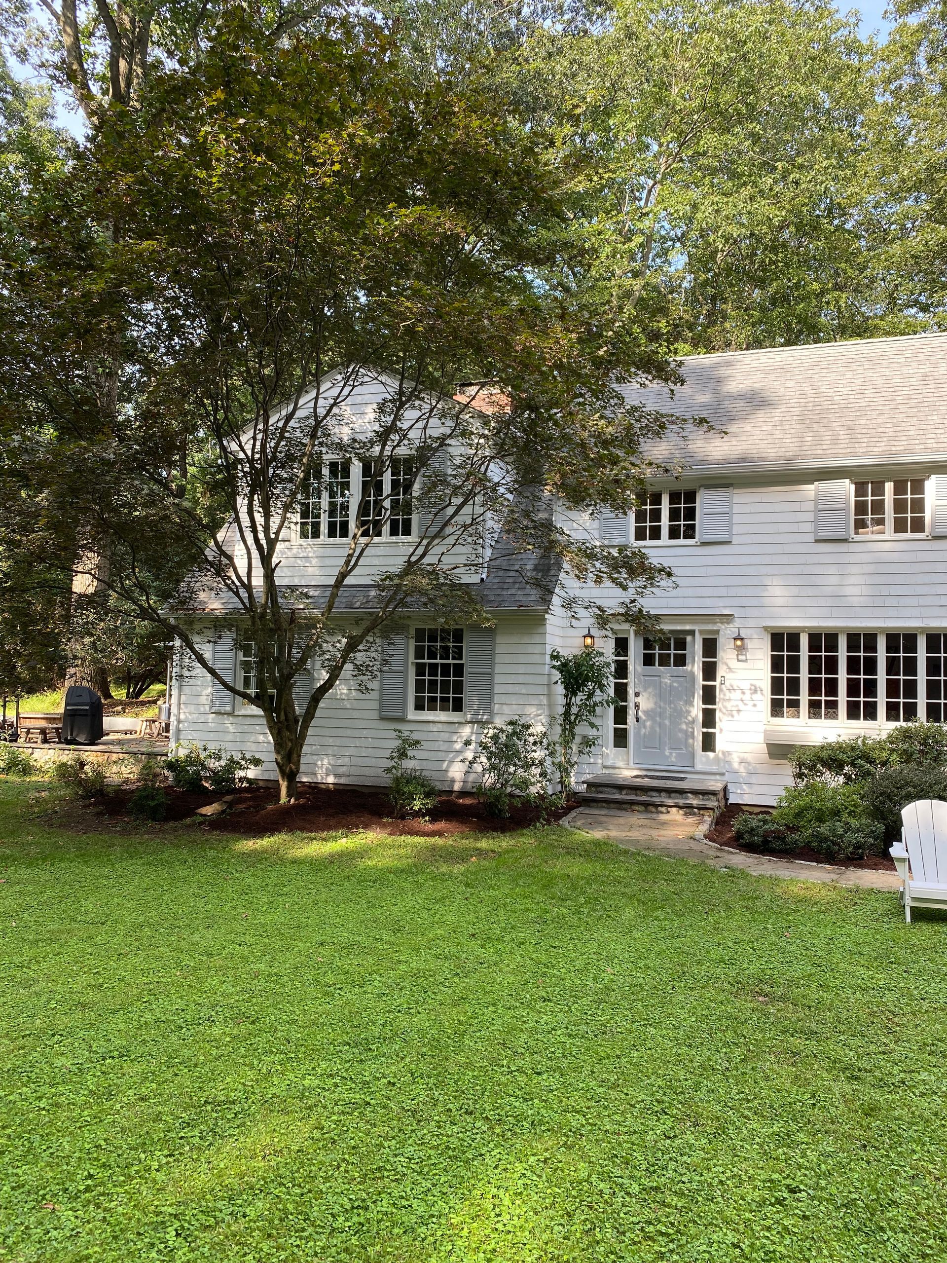 A large white house with a lush green lawn in front of it.