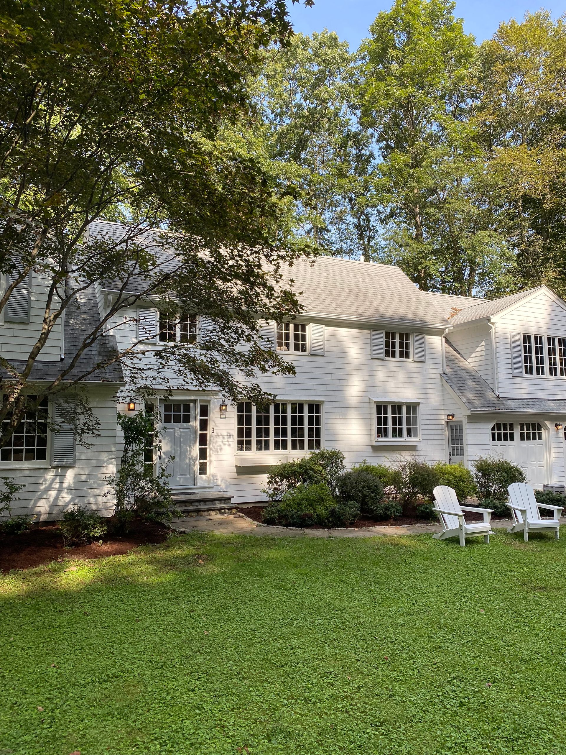 A large white house with a lush green lawn in front of it.