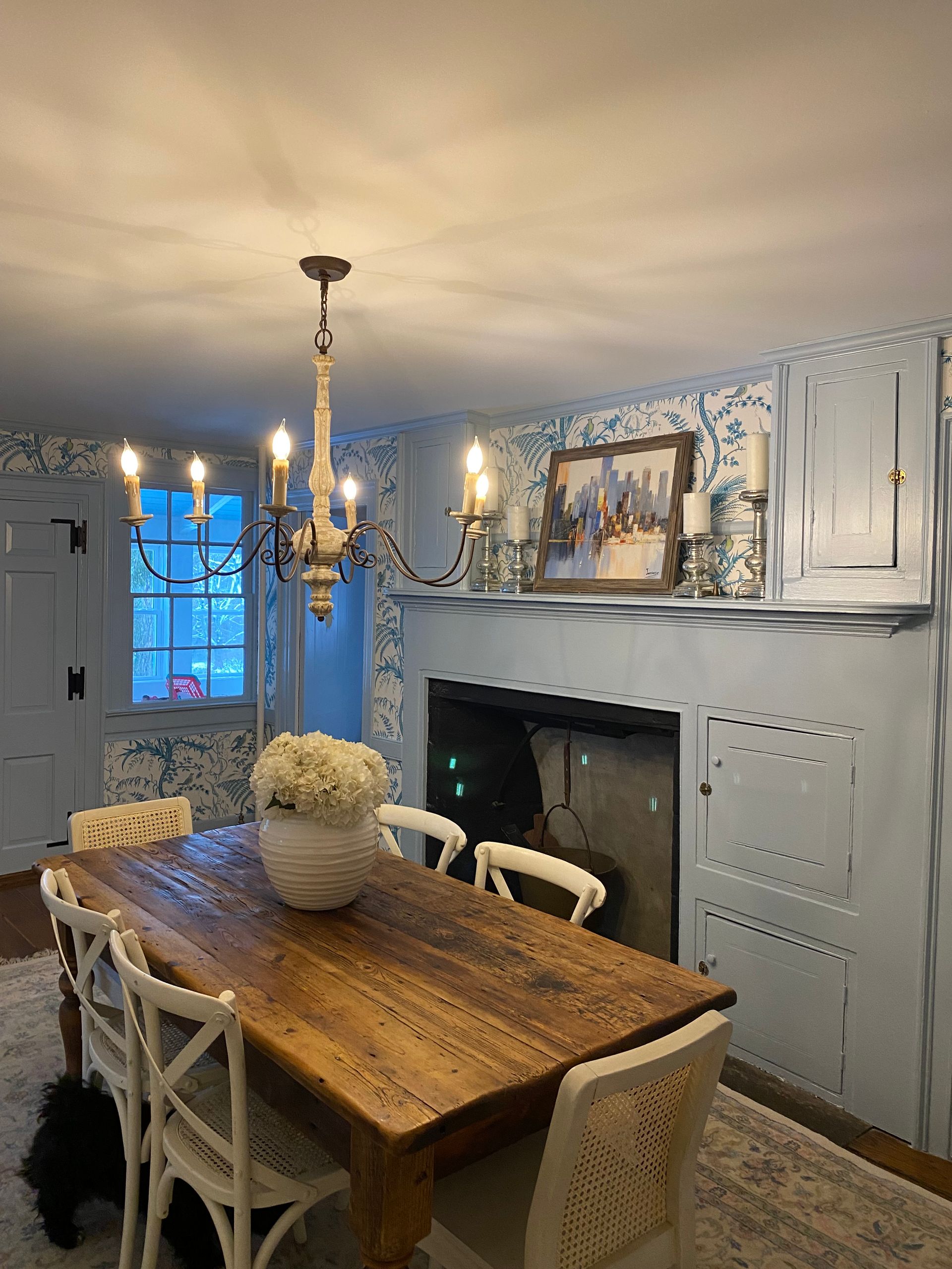 A dining room with a wooden table and chairs and a fireplace.