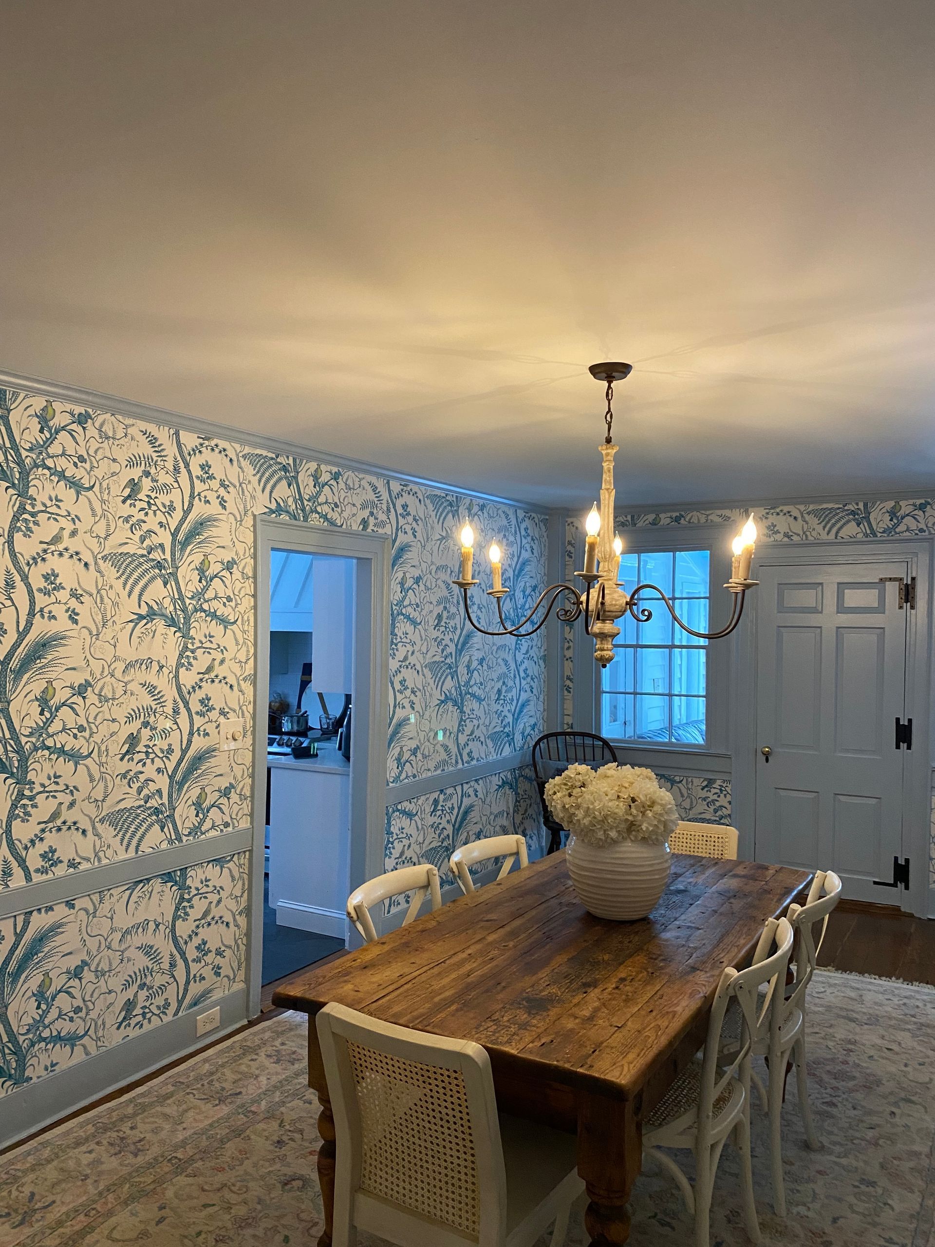 A dining room with a wooden table and chairs and a chandelier.