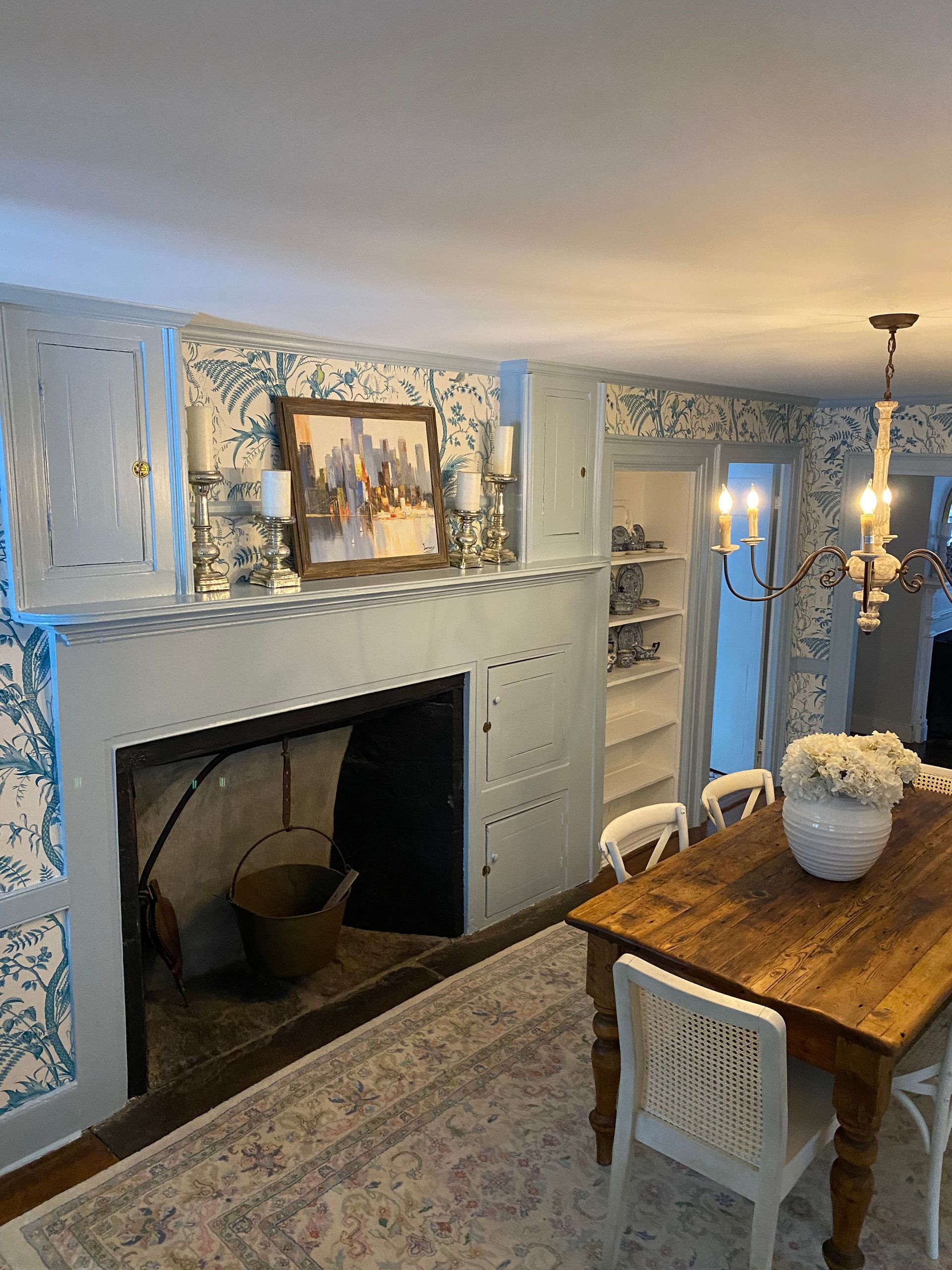 A dining room with a wooden table and chairs and a fireplace.