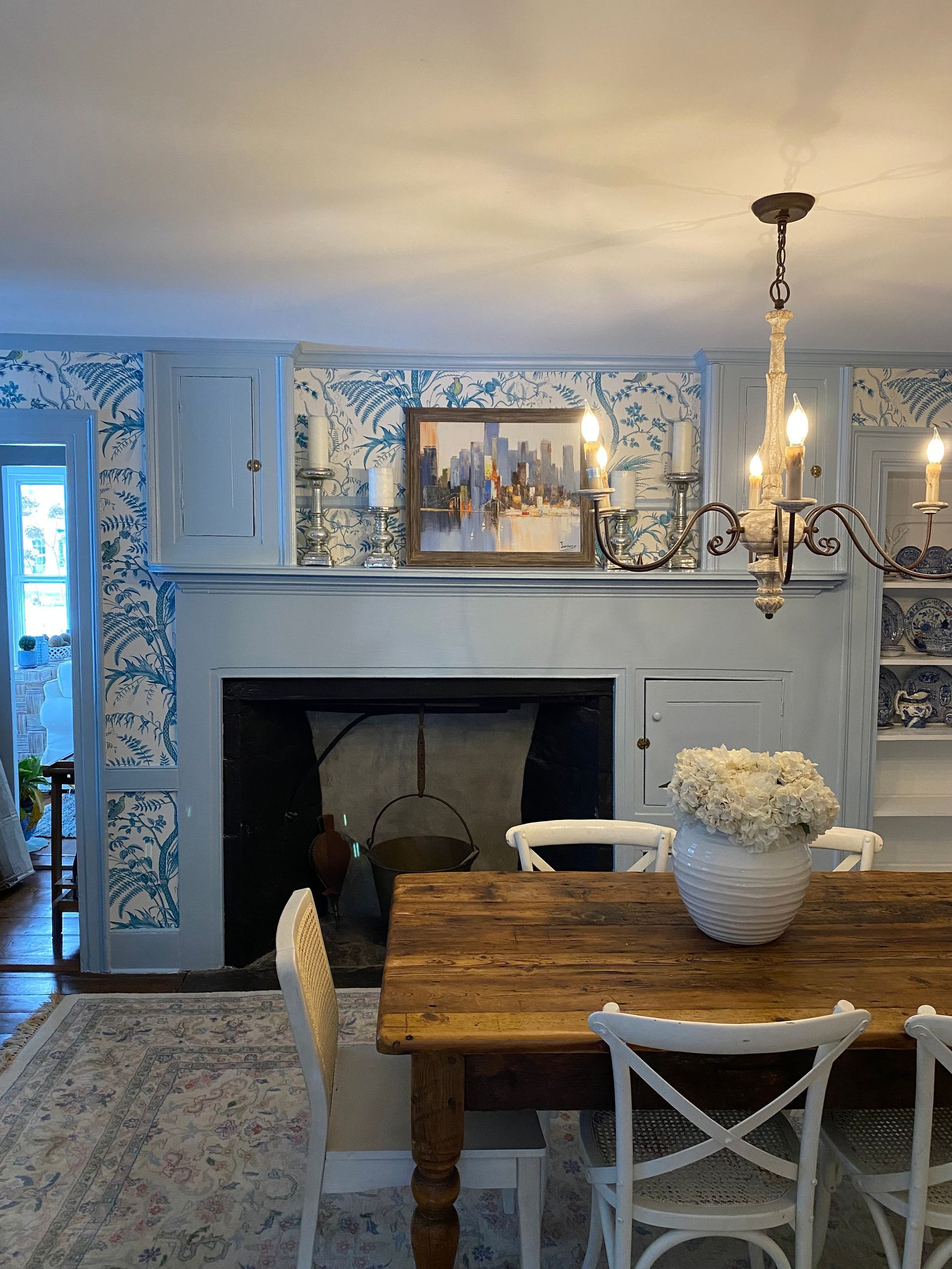 A dining room with a wooden table and chairs and a fireplace.