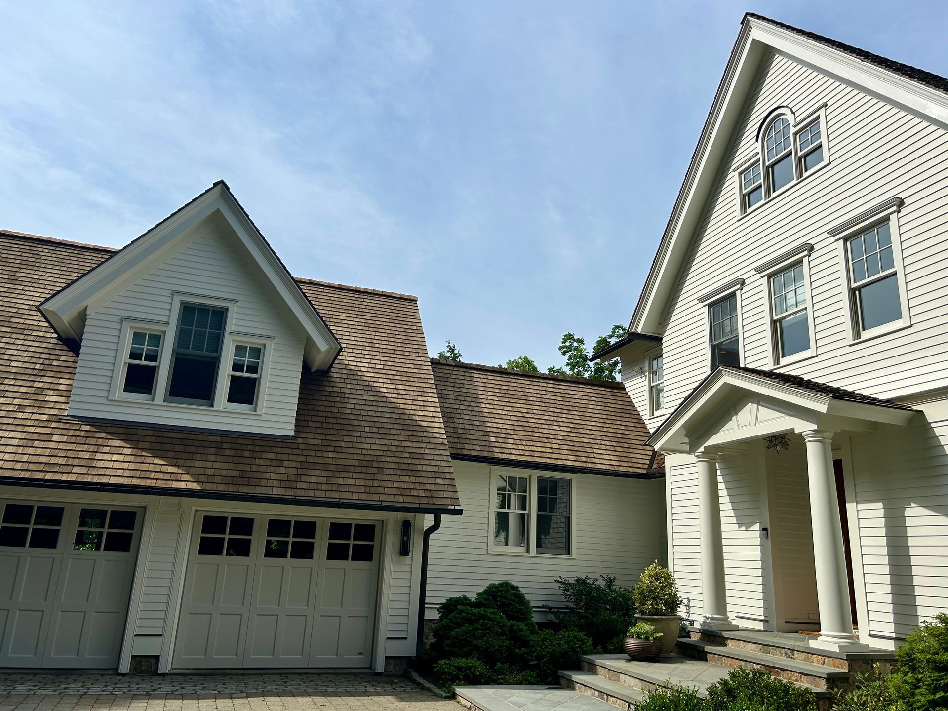 A white house with a brown roof and a garage