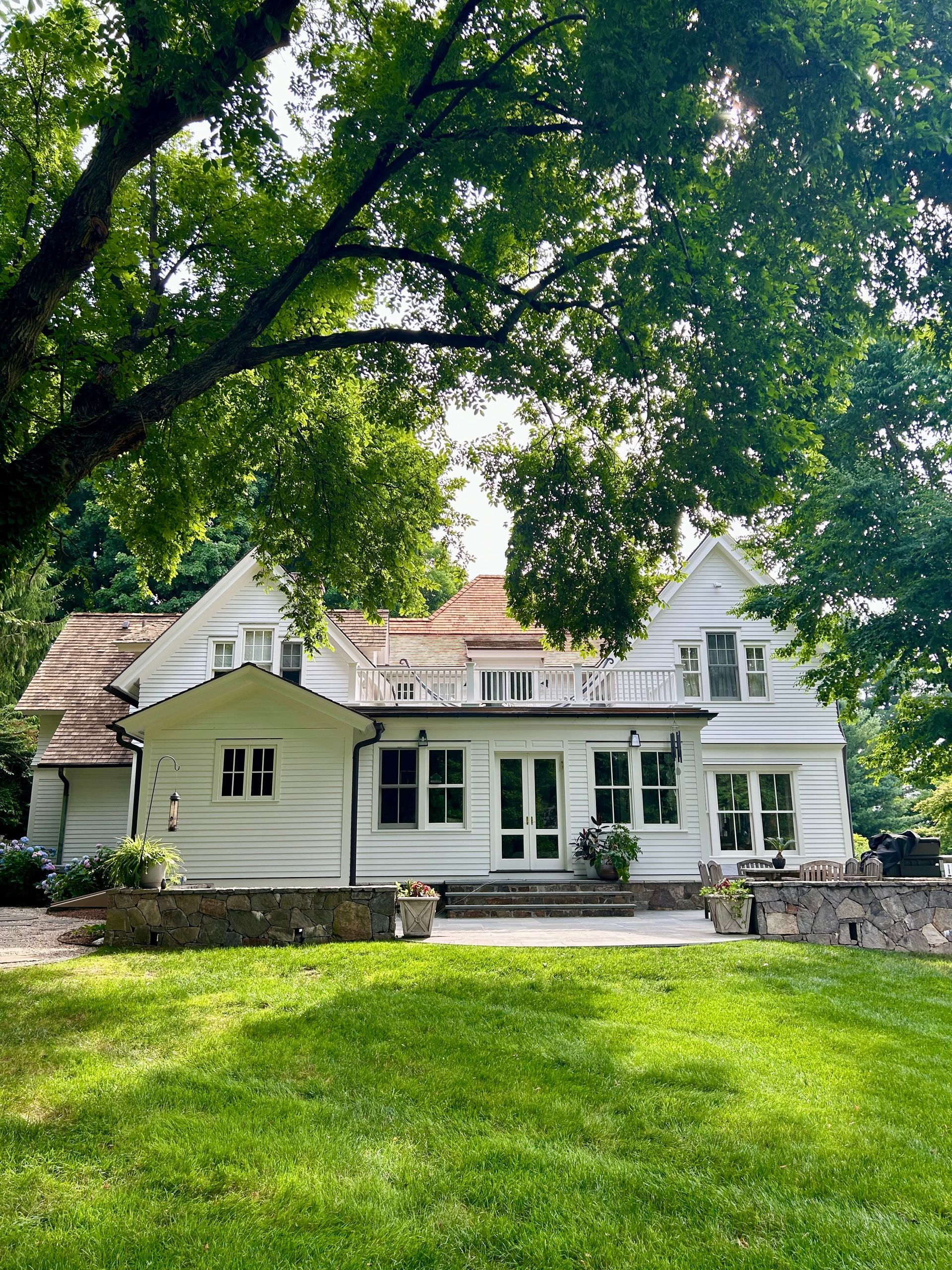 A large white house with a lot of windows is surrounded by trees.