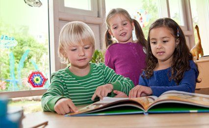 3 small girls reading a book