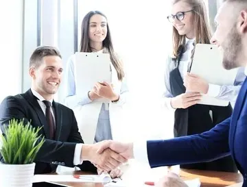 A group of business people are shaking hands in an office.