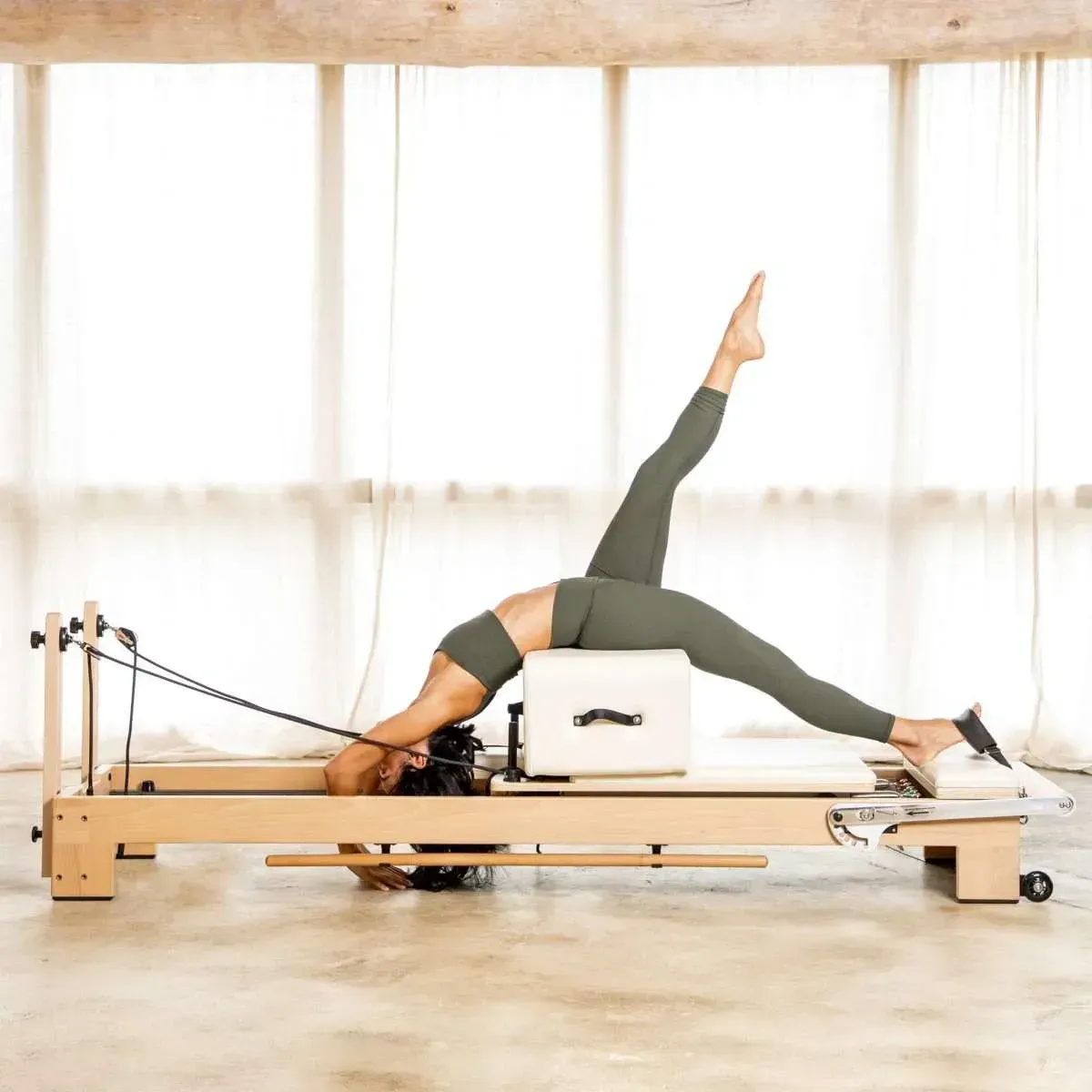 A woman is doing a yoga pose on a pilates machine.