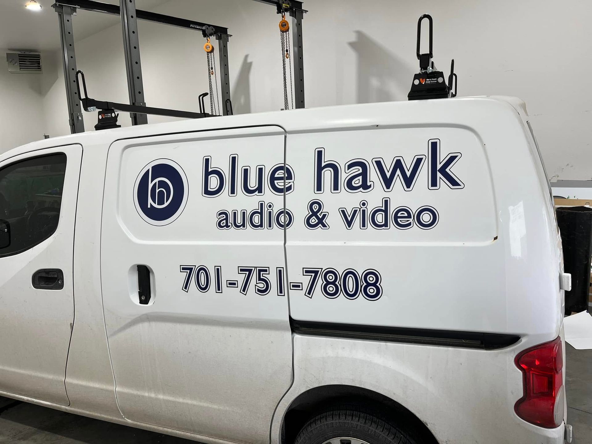 A white van with blue hawk audio and video written on it