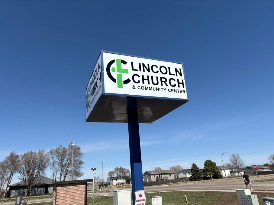 A sign for lincoln church is sitting on top of a blue pole.