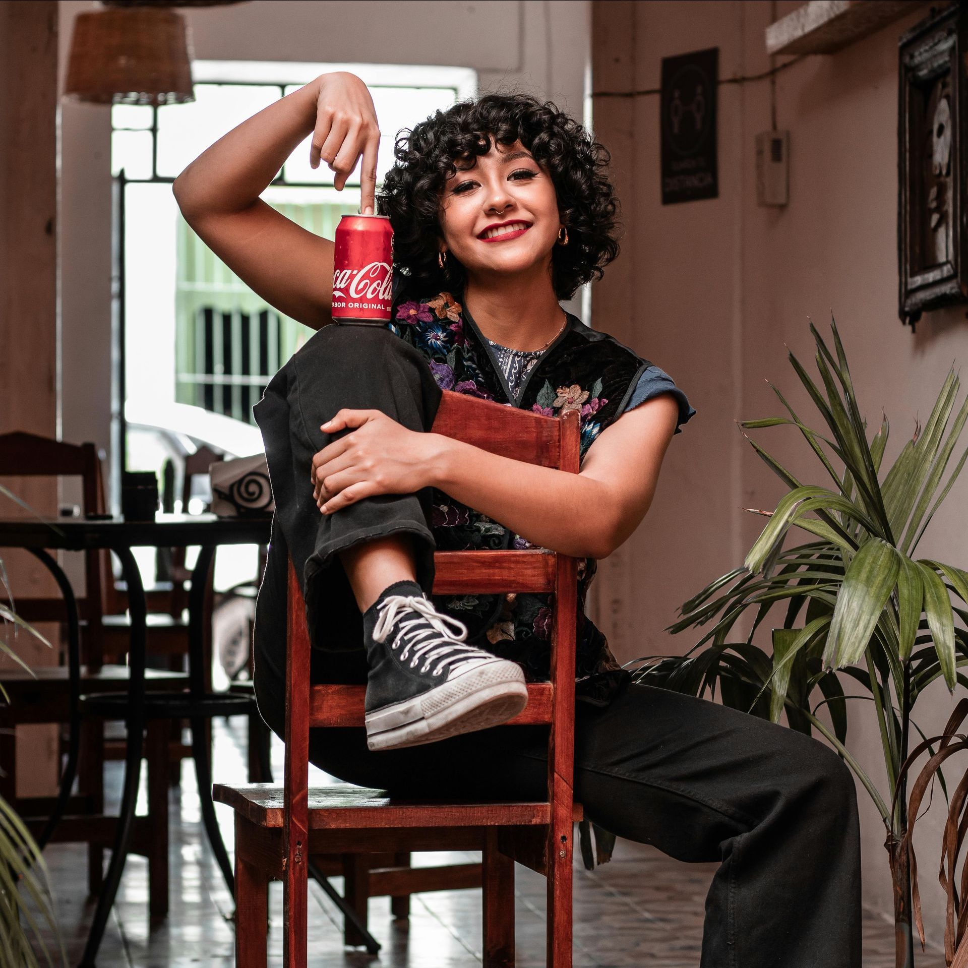 Smiling woman enjoying a Coca-Cola from a vending machine in a casual indoor space