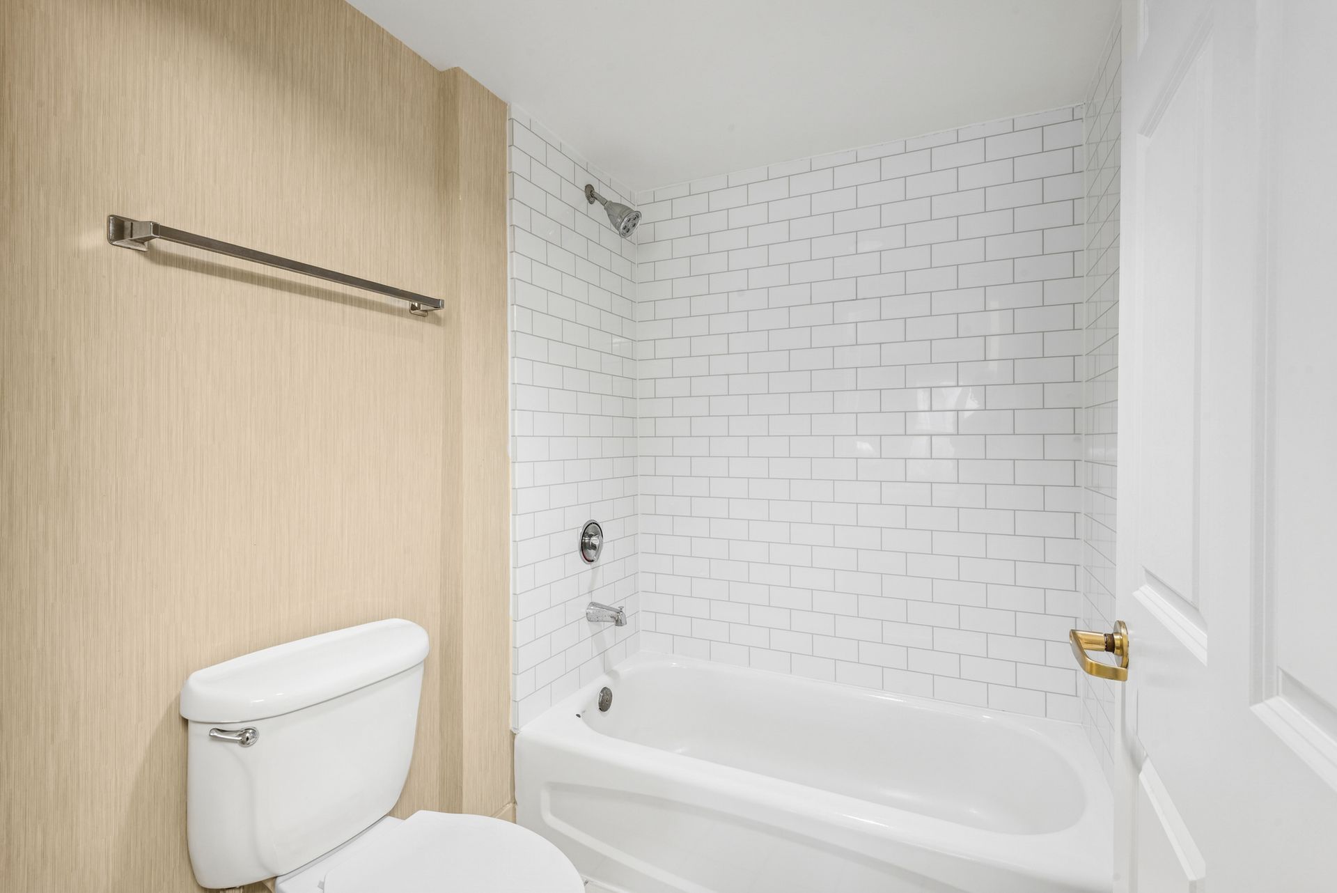 Bathroom interior with a white bathtub, toilet, and white tile shower.