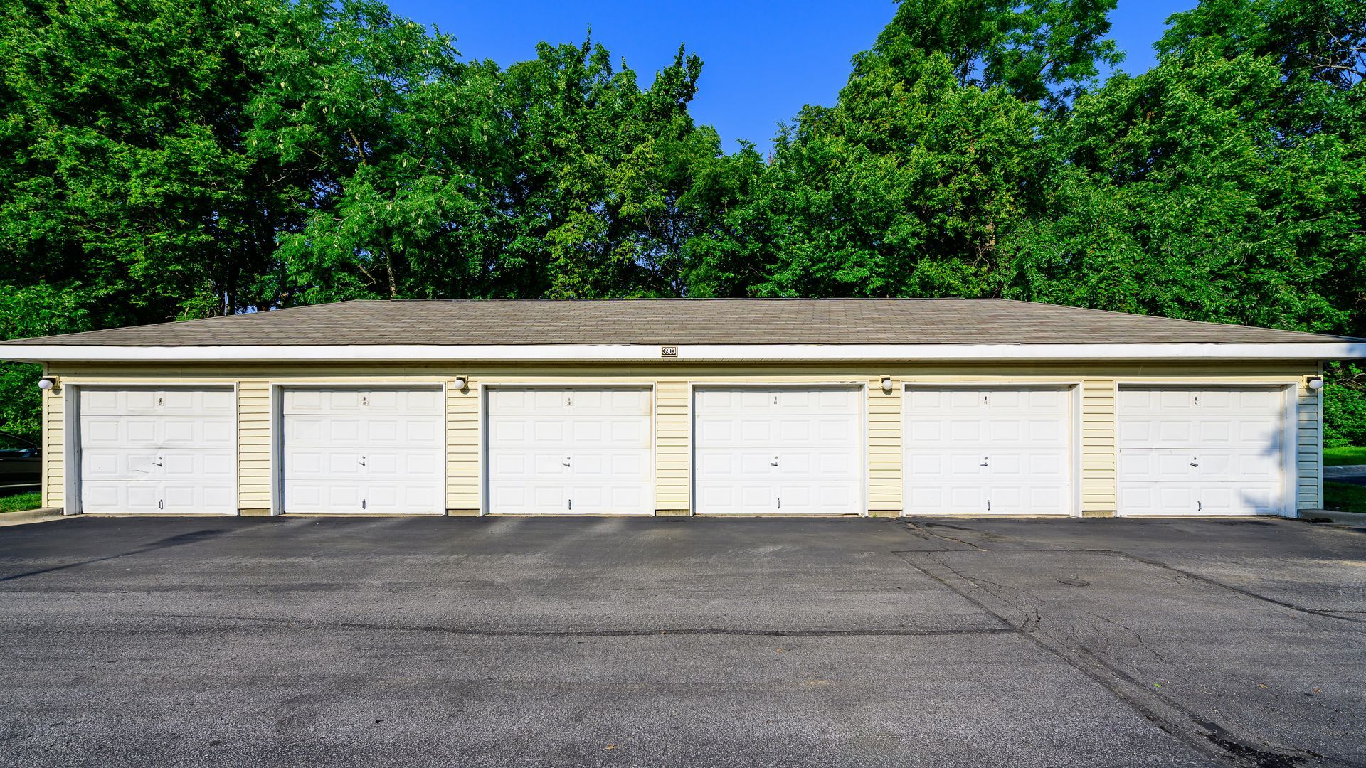 A row of white garage doors with trees in the background